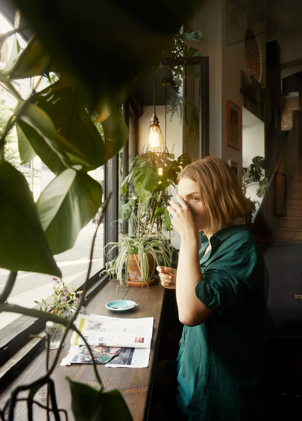 portrait of young student Lila drinking coffee at the window of a plant filled cafe in Clerkenwell
