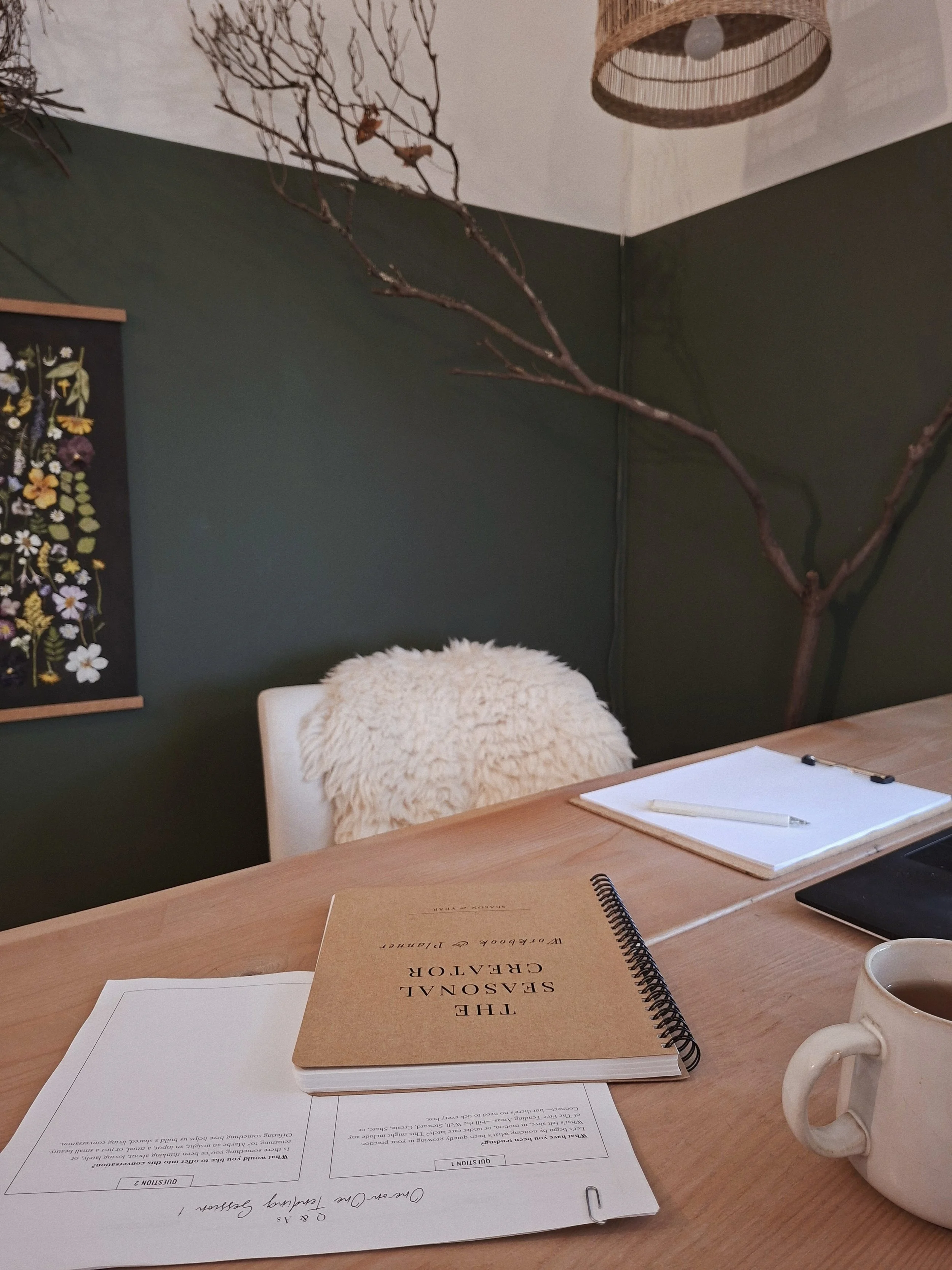 The Seasonal Creator Workbook & Planner on a pale wood table with session materials, notebook, laptop, and mug.