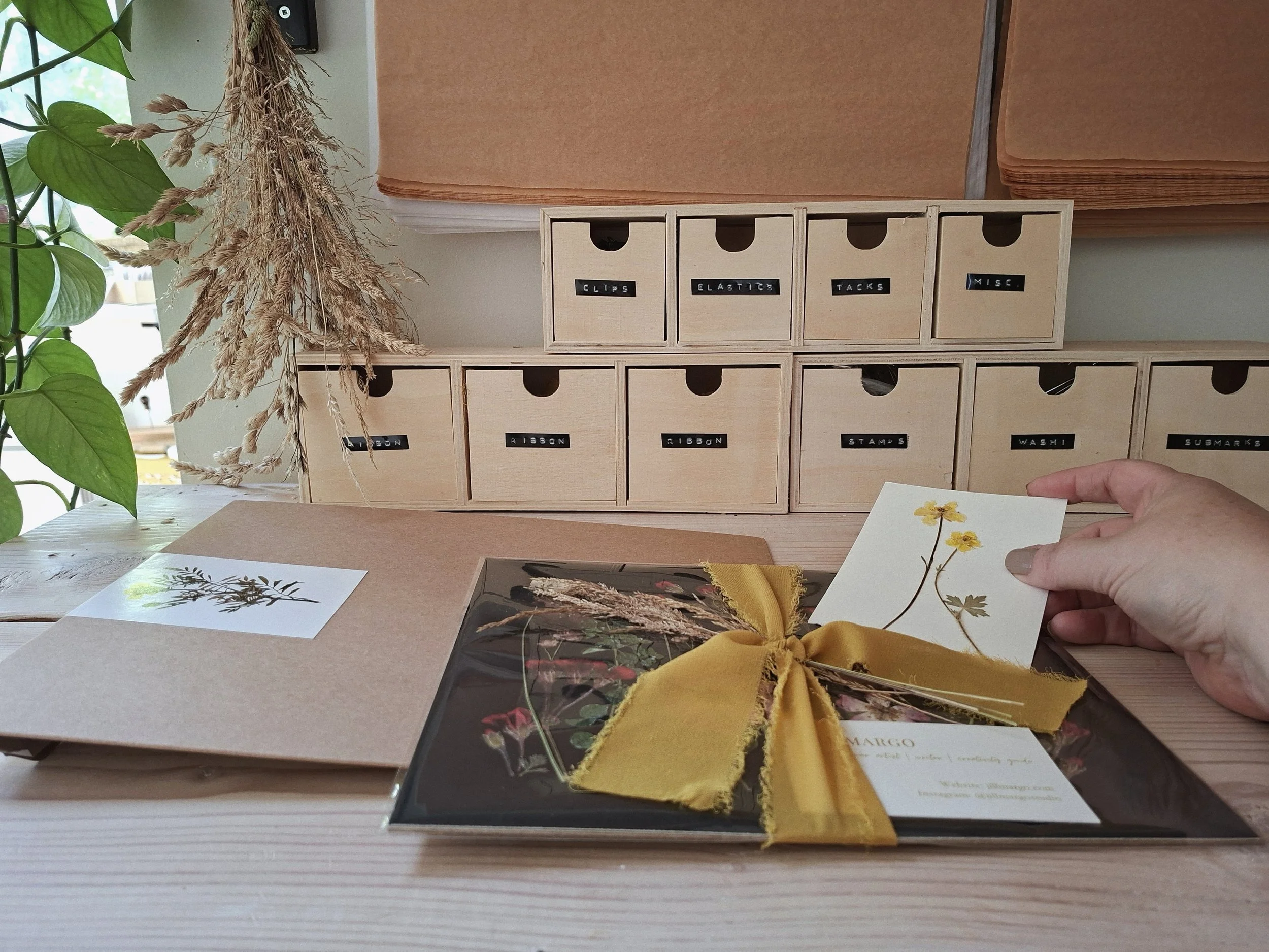 A Herbarium order being packaged at the studio shipping station, with botanical storage drawers in the background.