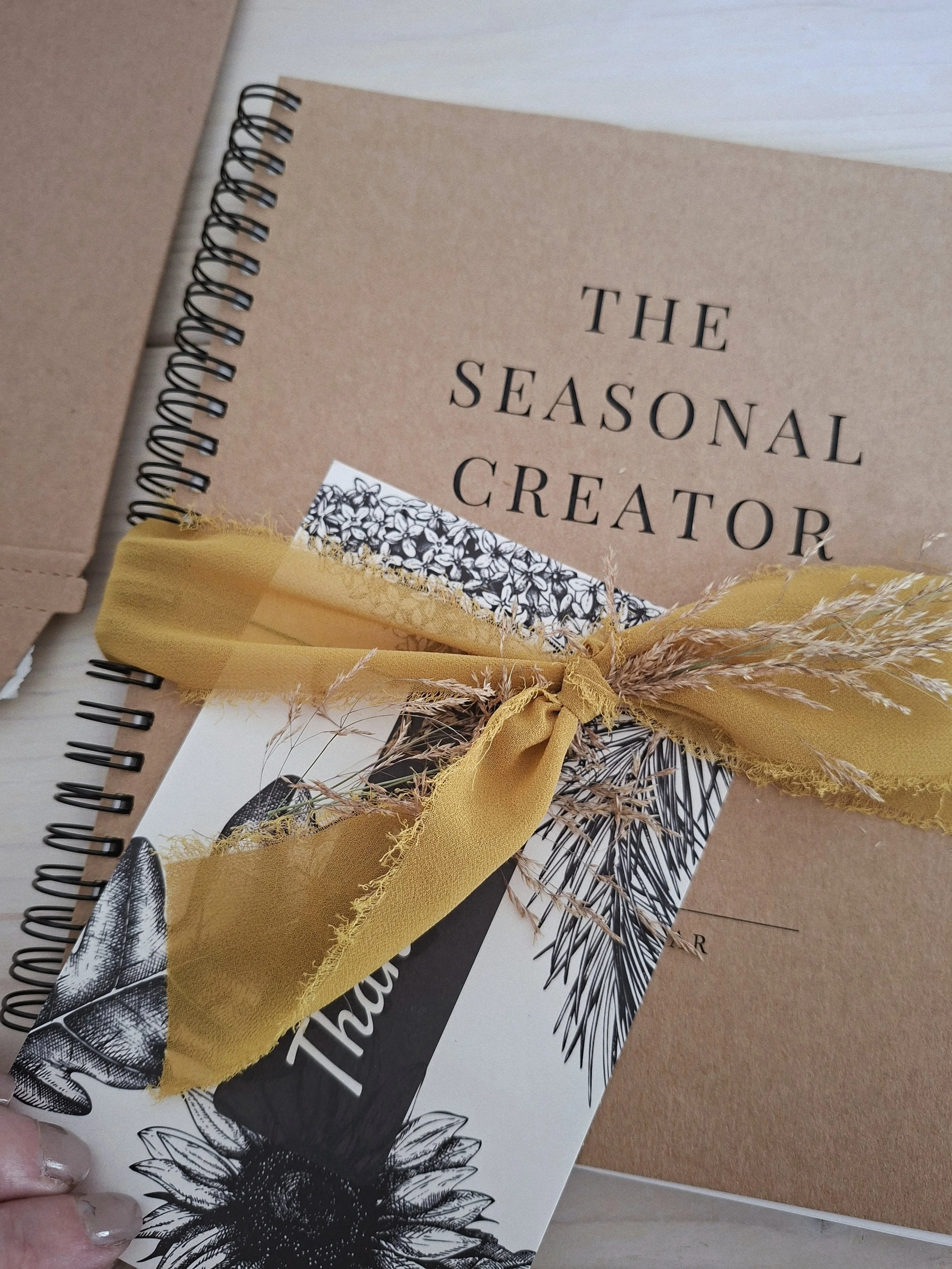 A Seasonal Creator Workbook & Planner packaged with a botanical thank-you card and ochre ribbon, ready for an Individual Tending Sessions participant.