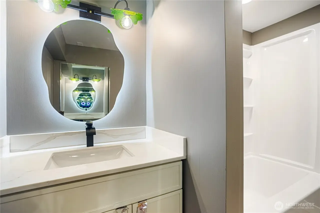 Bathroom sink and mirror with a reflection showing a robot face and lights in the mirror.