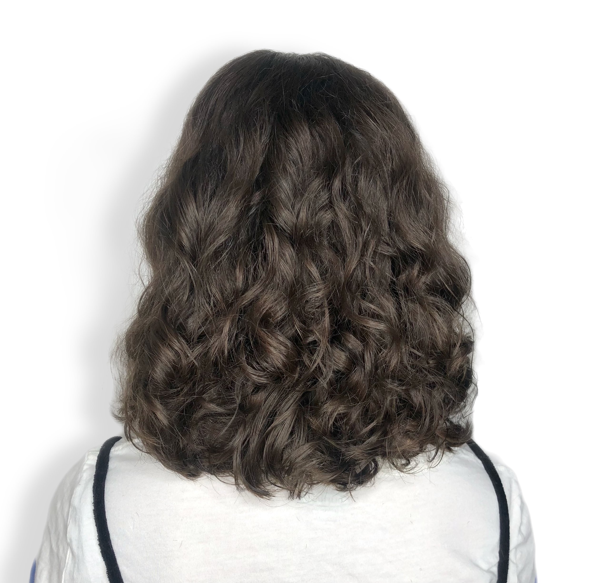 Back view of a person with shoulder-length curly dark brown hair wearing a white shirt with black trim.