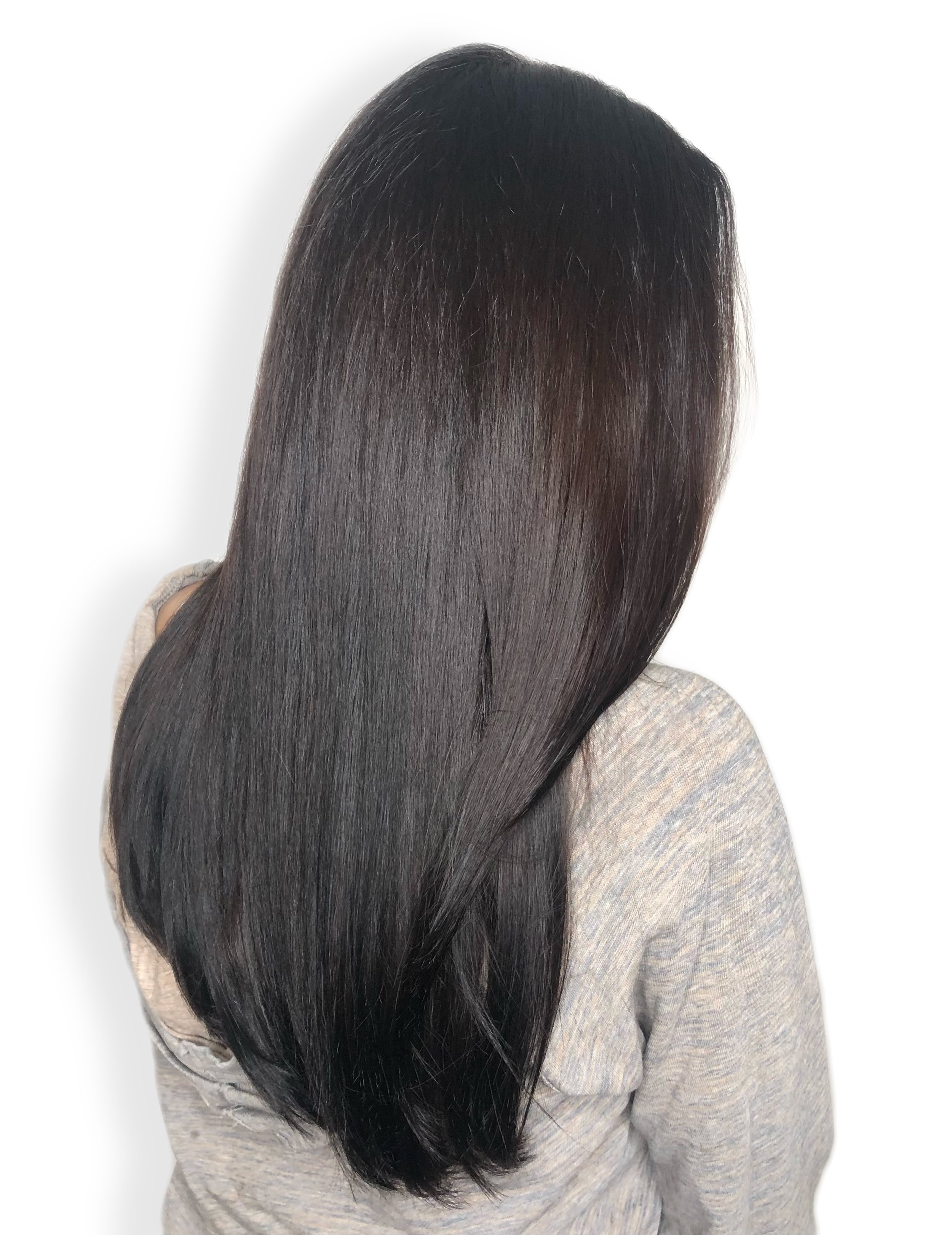 Woman with long, straight, shiny black hair, wearing a gray sweater, viewed from the side.