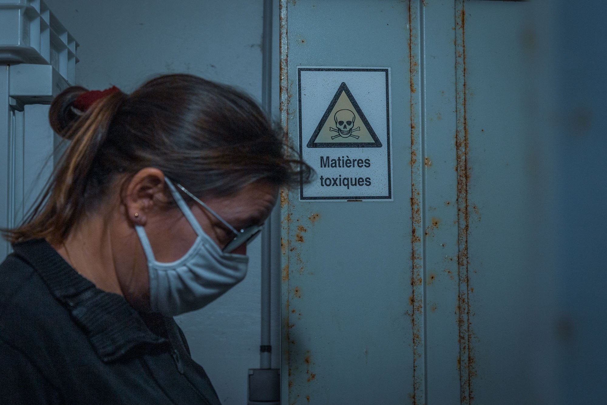 Une chercheur chimiste masquée devant la porte de la chambre fr