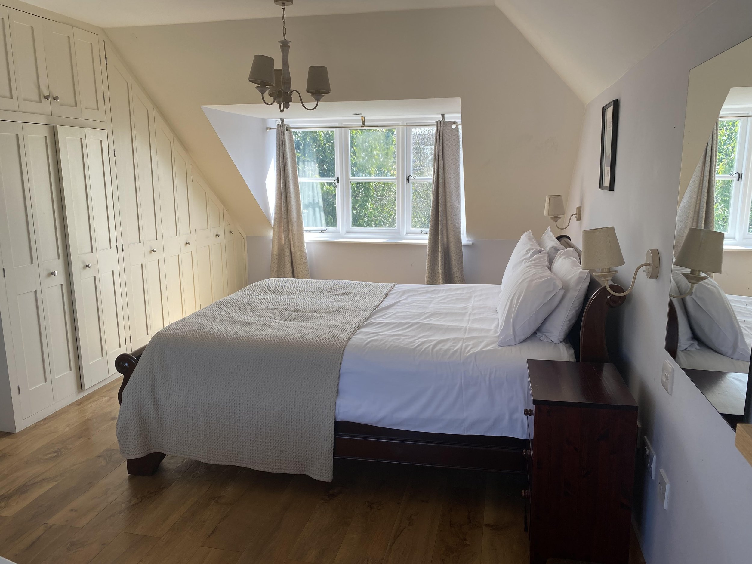 Primary bedroom suite with king size bed and views of the garden, perfect for a romantic weekend in your Cotswold holiday home.