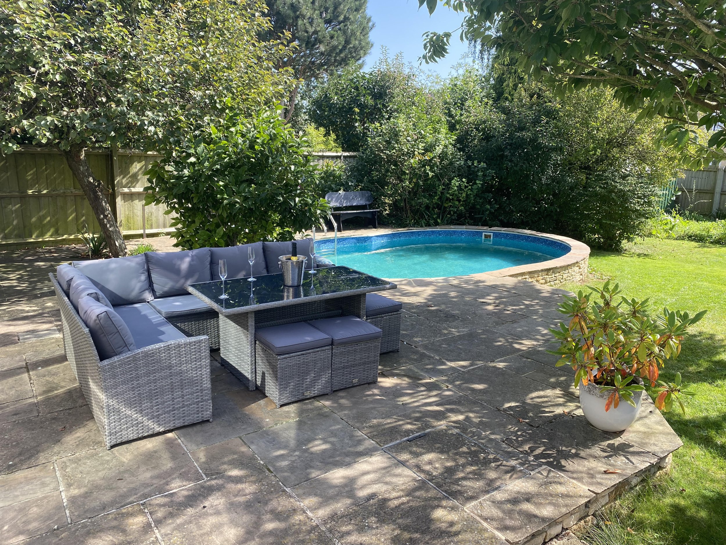 Private swimming pool and garden leading off patio area that adjoins open plan dining area from main house in Cotswolds area of UK.