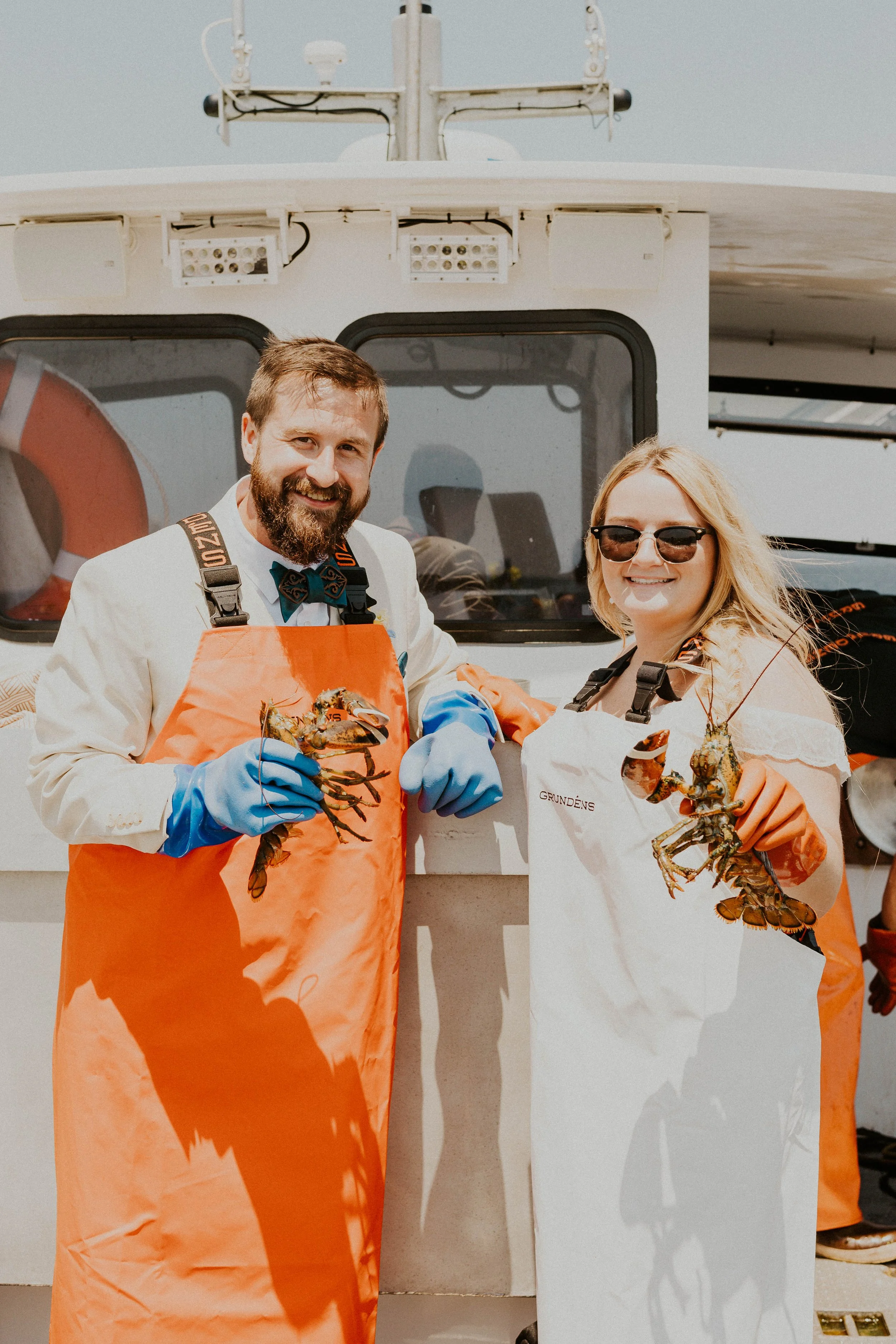 Bride and groom in their Grundens holding lobsters