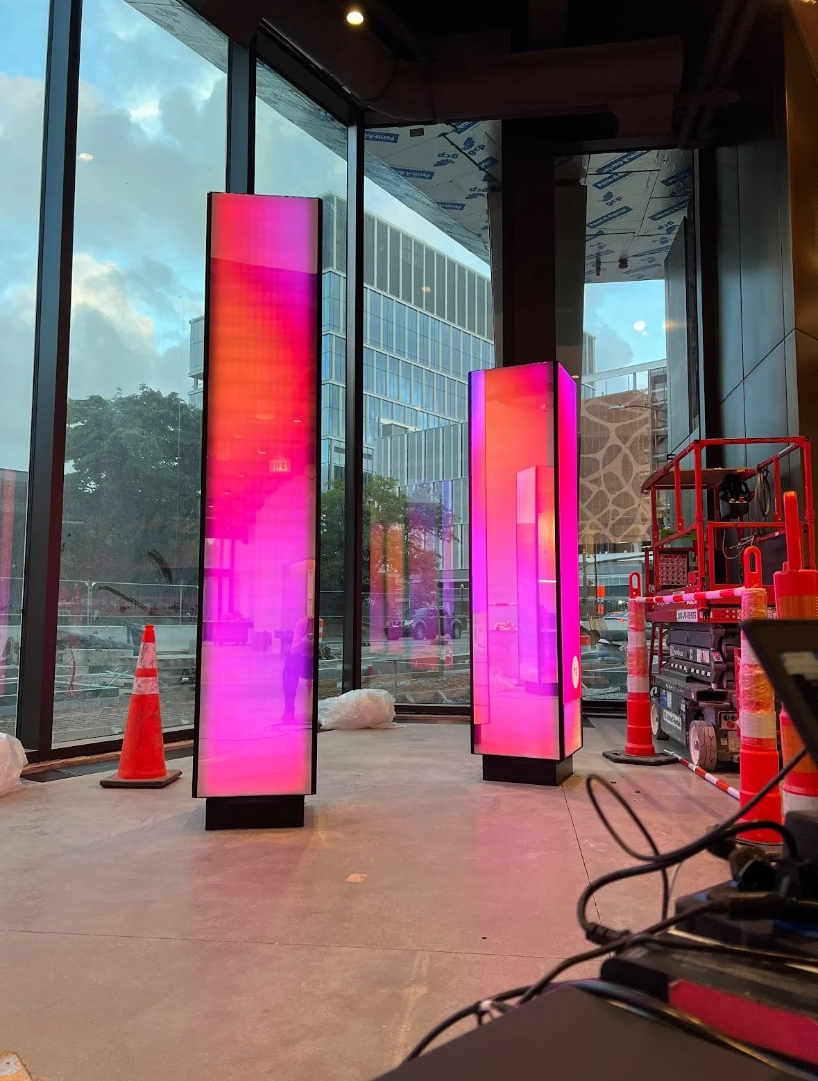 Reflection is a public artwork and installation art sculpture design featuring four towers that feature a reflective mirrored surface during the day and at dusk glow with colorful light, a representation of the building metrics collected by this LEED