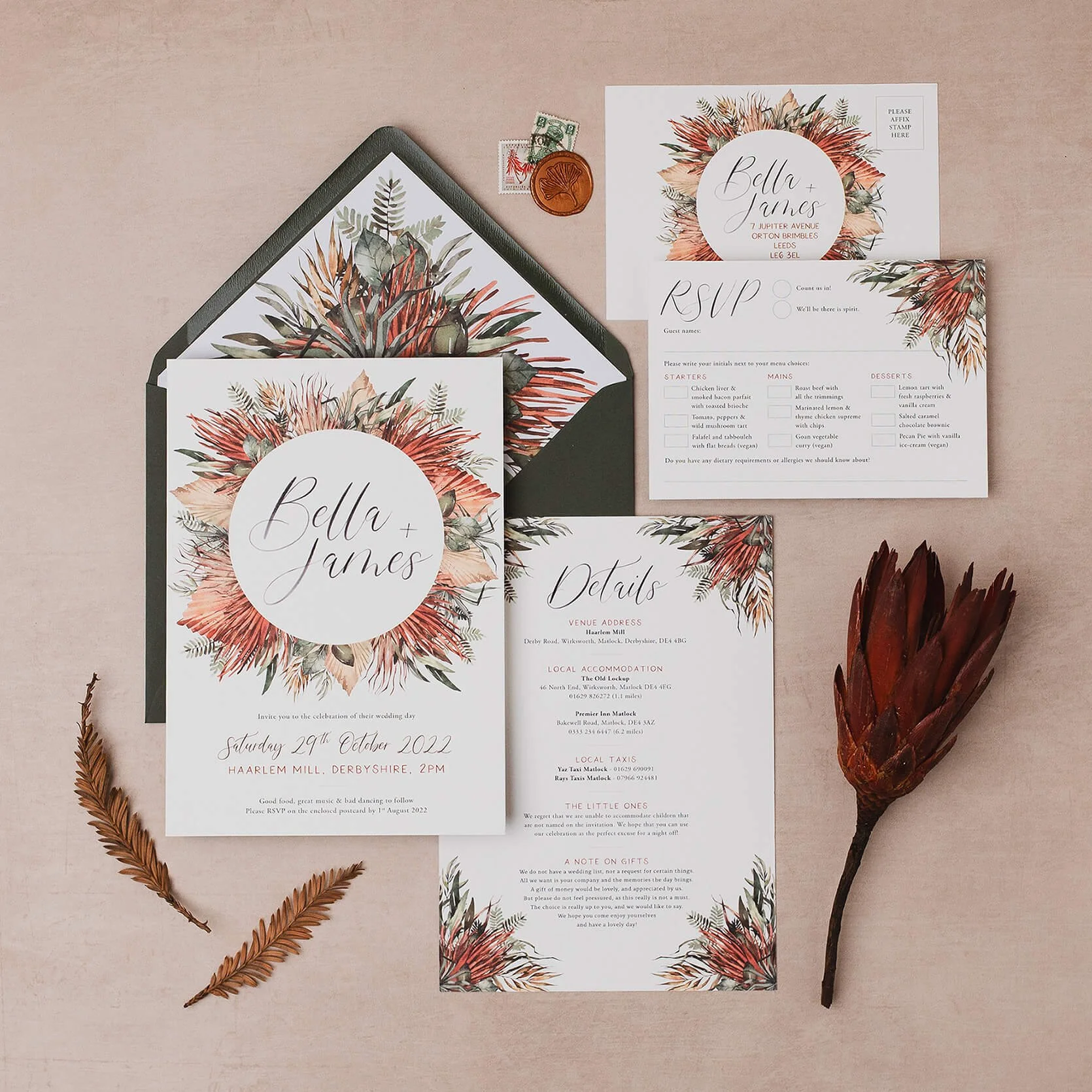 Wedding invitation set with floral designs, RSVP card, details card, and envelope featuring a tropical plant theme in pink, green, and beige tones. There are also dried leaves and a large dried flower on a pink background.