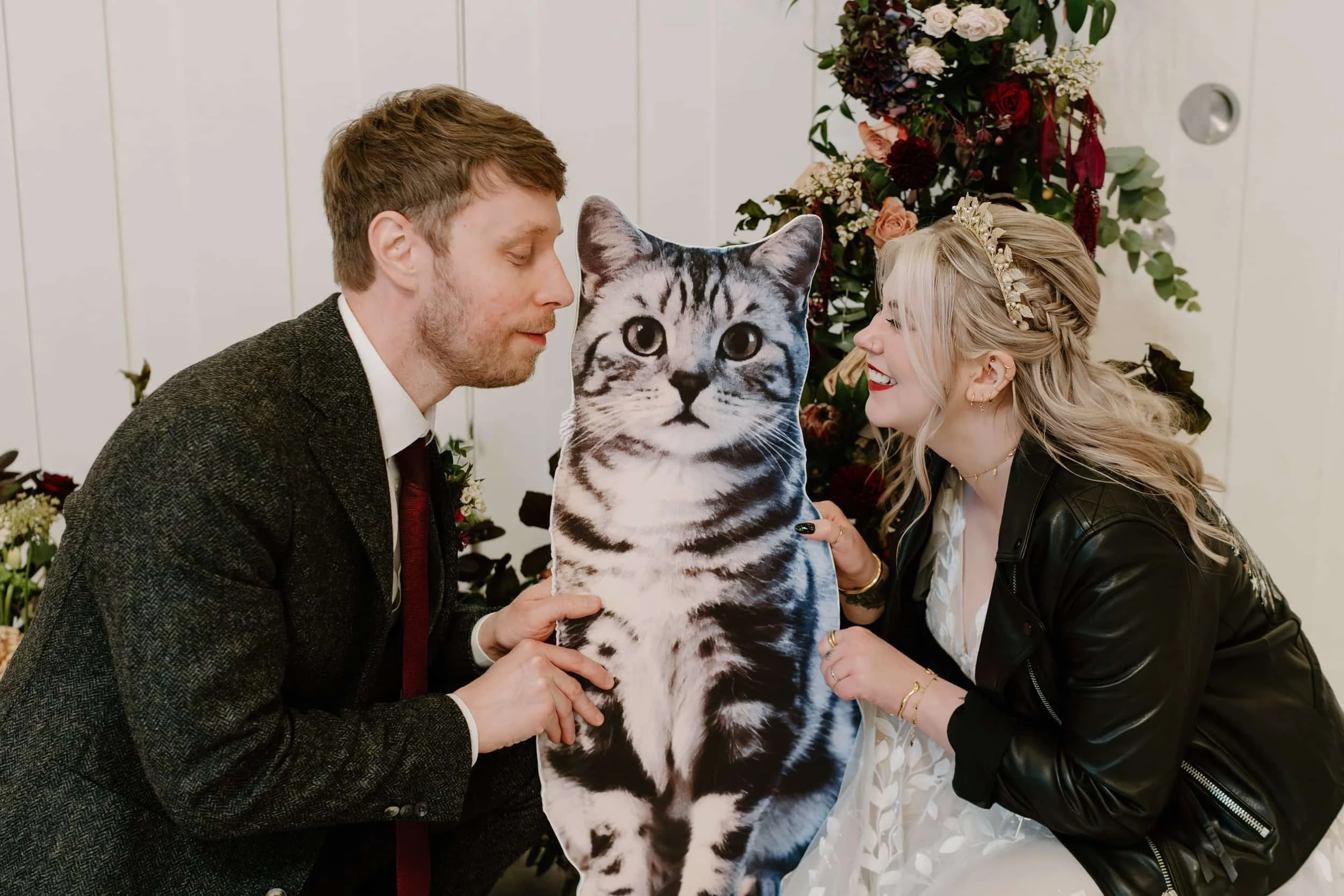 A bride and groom with a cardboard cut out of their cat at their wedding.