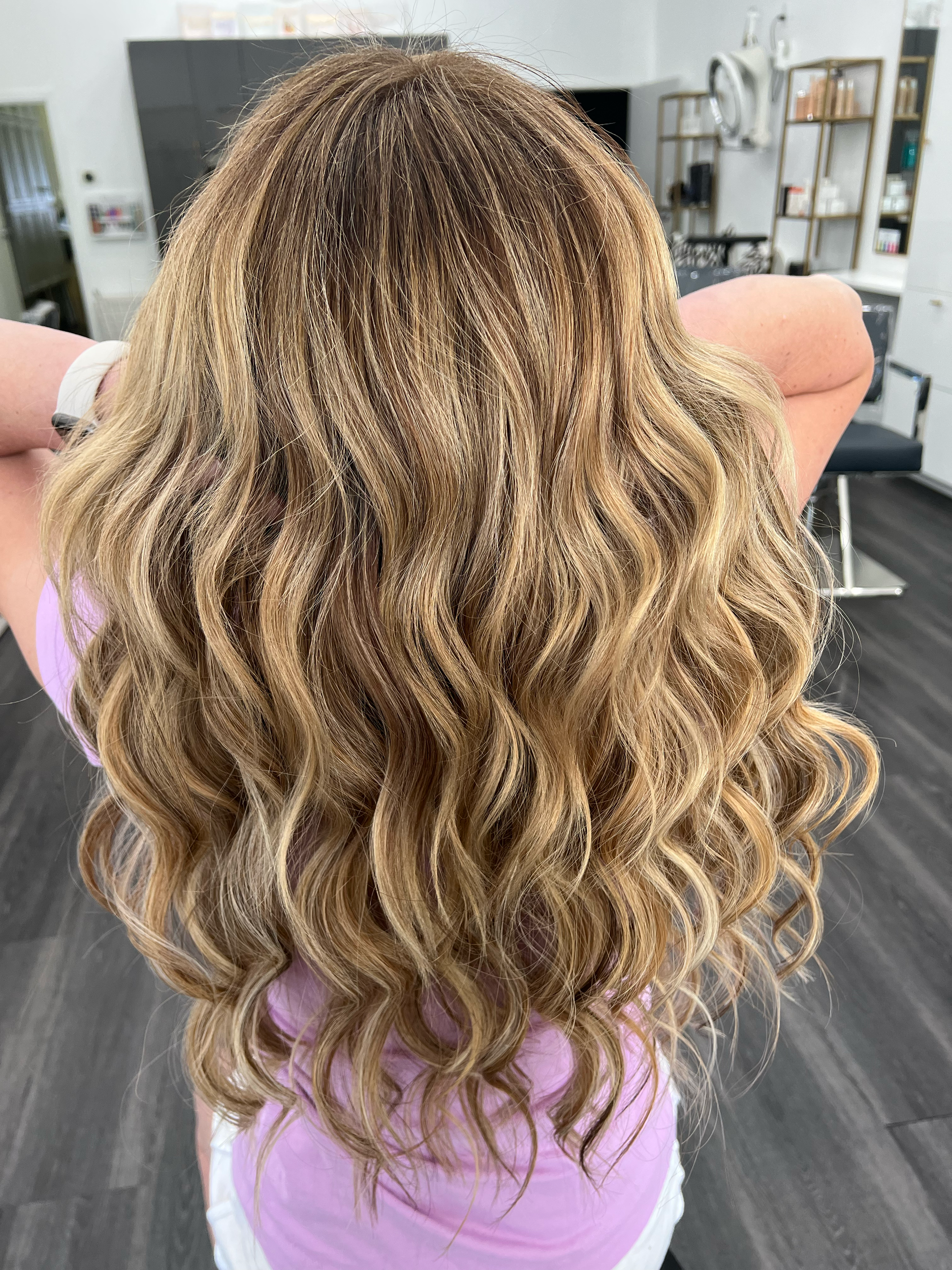Woman with blonde, wavy hair sitting in a hair salon.