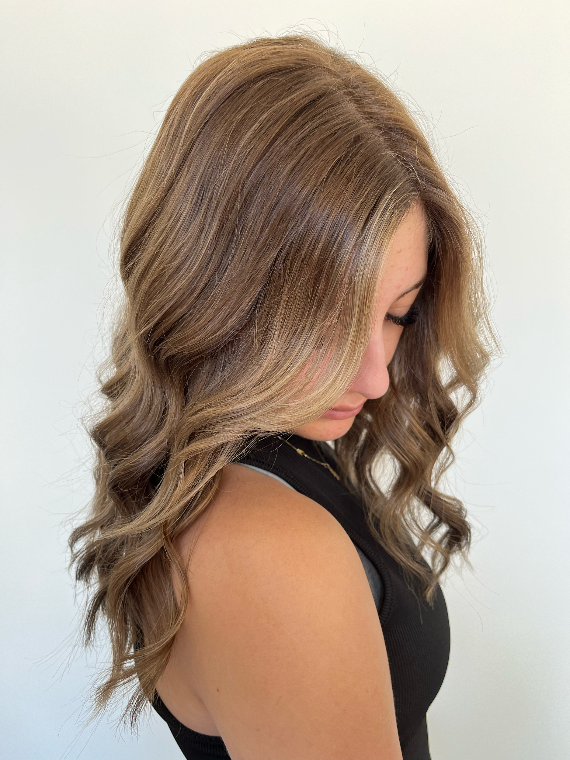 Close-up of a woman with wavy, blonde hair, lying on her side with her eyes closed.