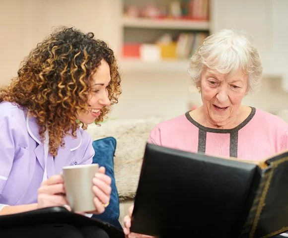 Elderly woman with caregiver at home looking at a photo album - memory care in Redmond, OR