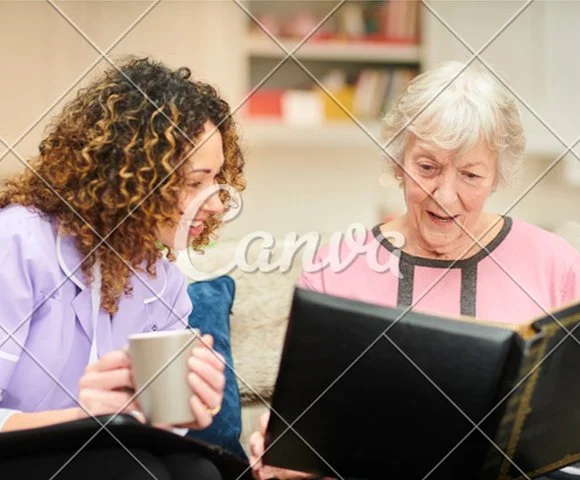 Elderly woman with caregiver at home looking at a photo album - memory care in Redmond, OR
