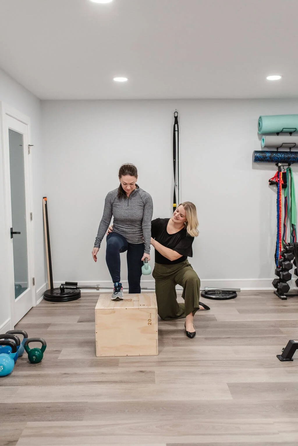 A pelvic floor PT using a kettlebell with a patient practicing pelvic floor exercises on a patient in pelvic floor rehab.