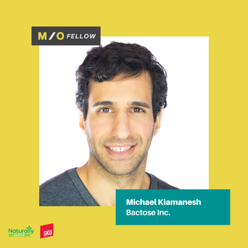 A headshot of a man with dark, curly hair smiling against a white background with a yellow border, with text indicating he is Michael Kiamanesh from Bactose Inc. and a M/O Fellow.