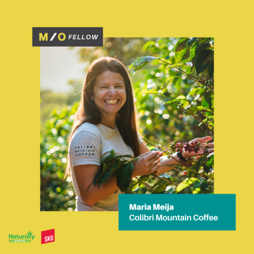 Woman smiling and picking coffee cherries from a plant in a coffee orchard.
