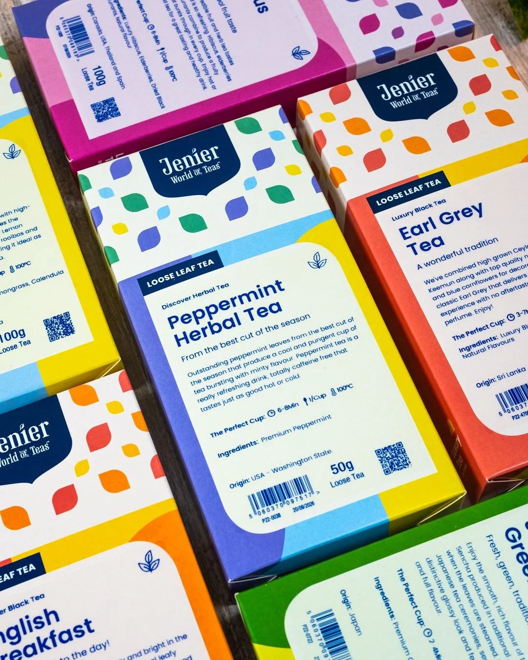 Boxes of loose leaf tea flavors, including peppermint herbal tea and Earl Grey tea, from the brand Jenier. The packaging features colorful patterns and detailed descriptions of each tea.