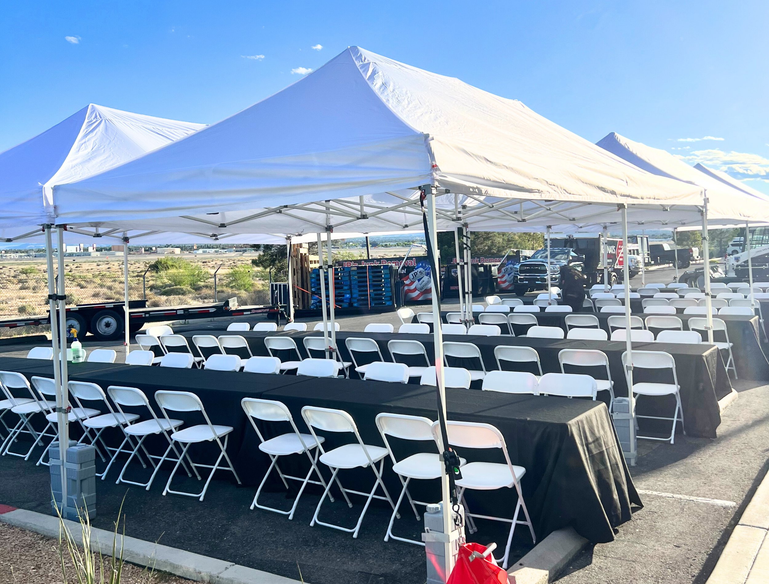 Corporate event tent rental with tables, chairs and white linens setup