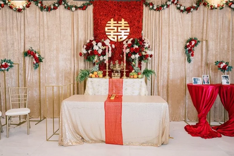 Traditional Chinese wedding altar with double happiness symbol, red and gold decoration, and floral arrangements.