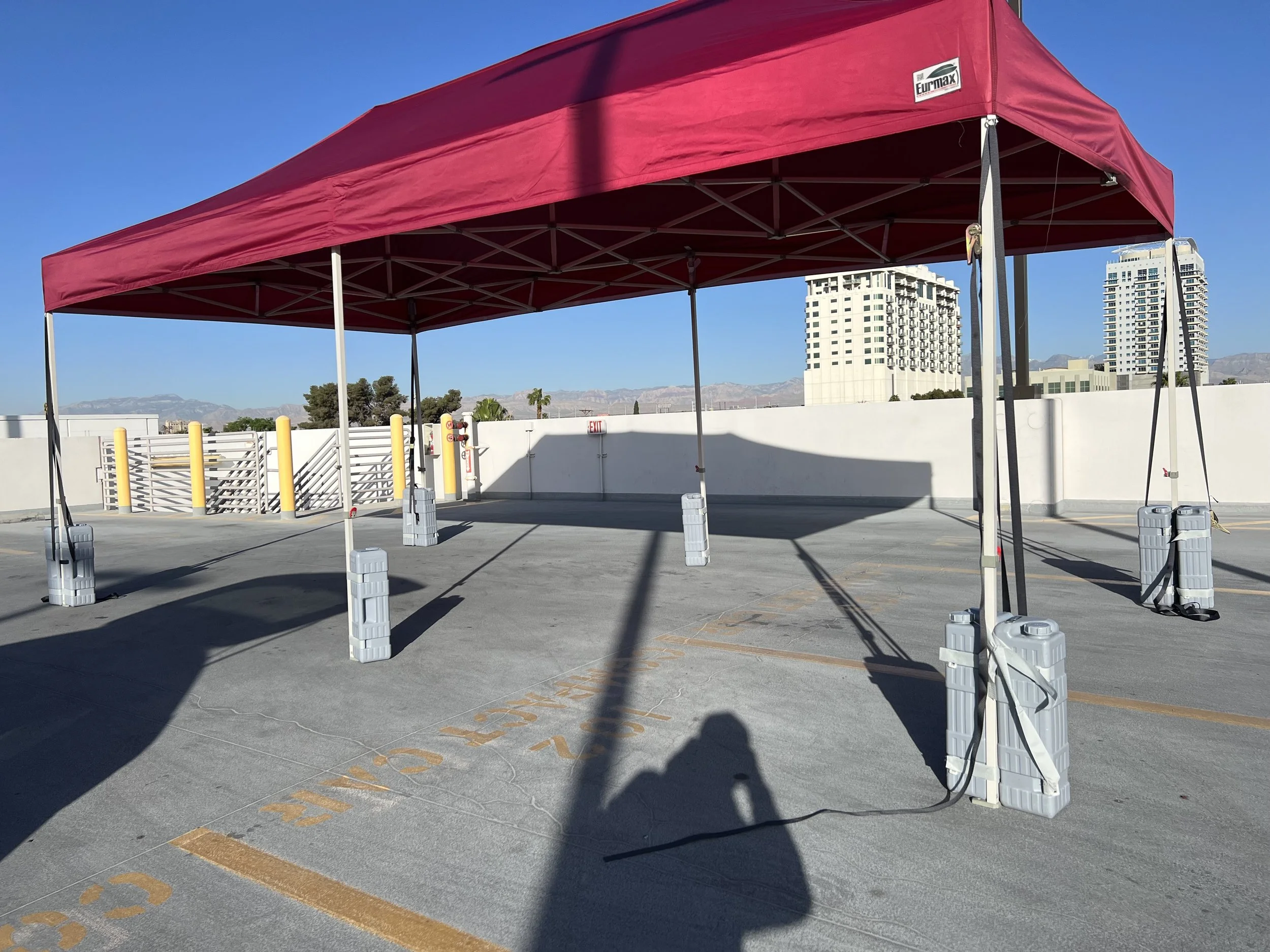 Red canopy tent on rooftop parking with skyscrapers in background