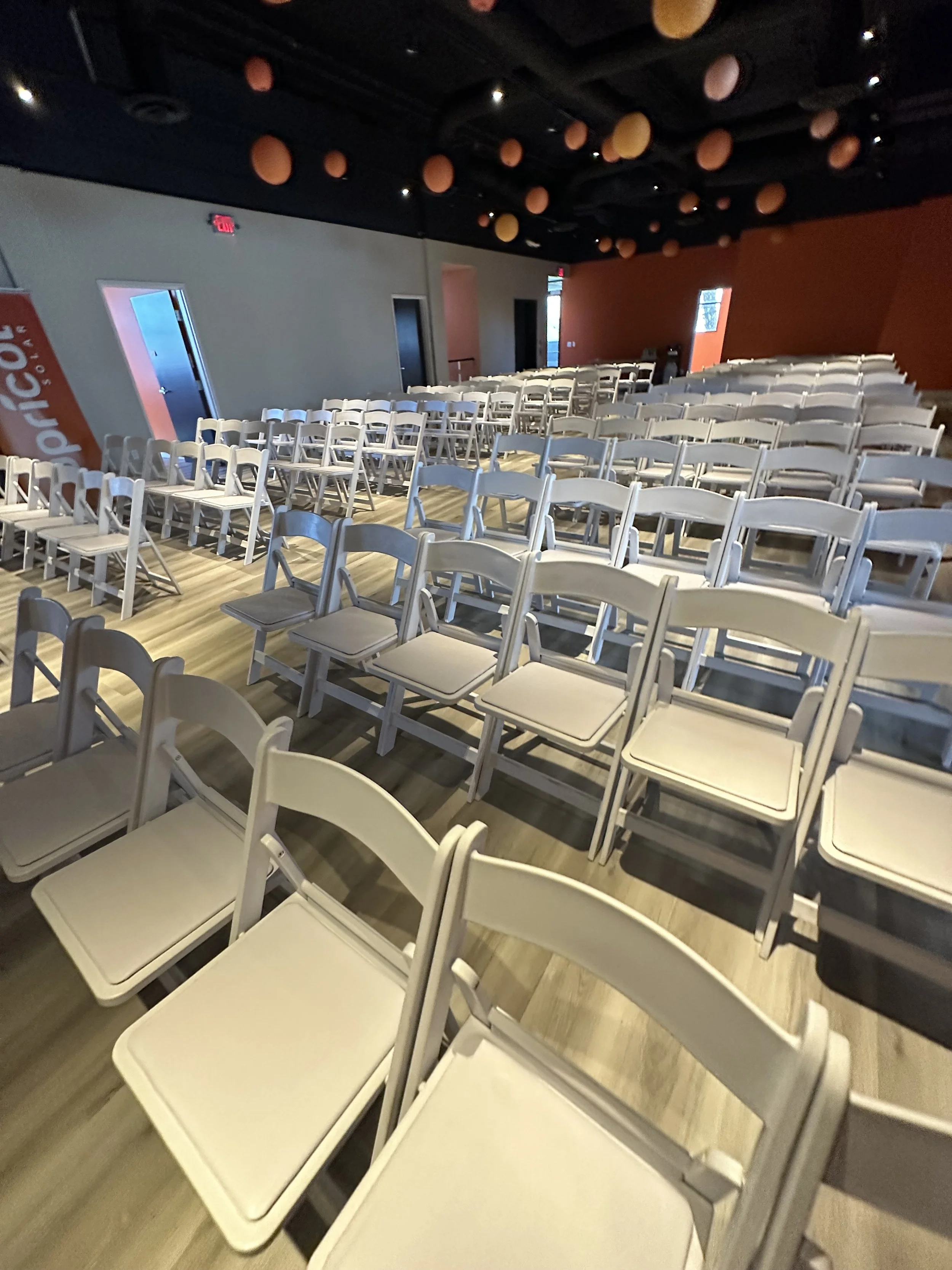Empty event hall with rows of white folding chairs
