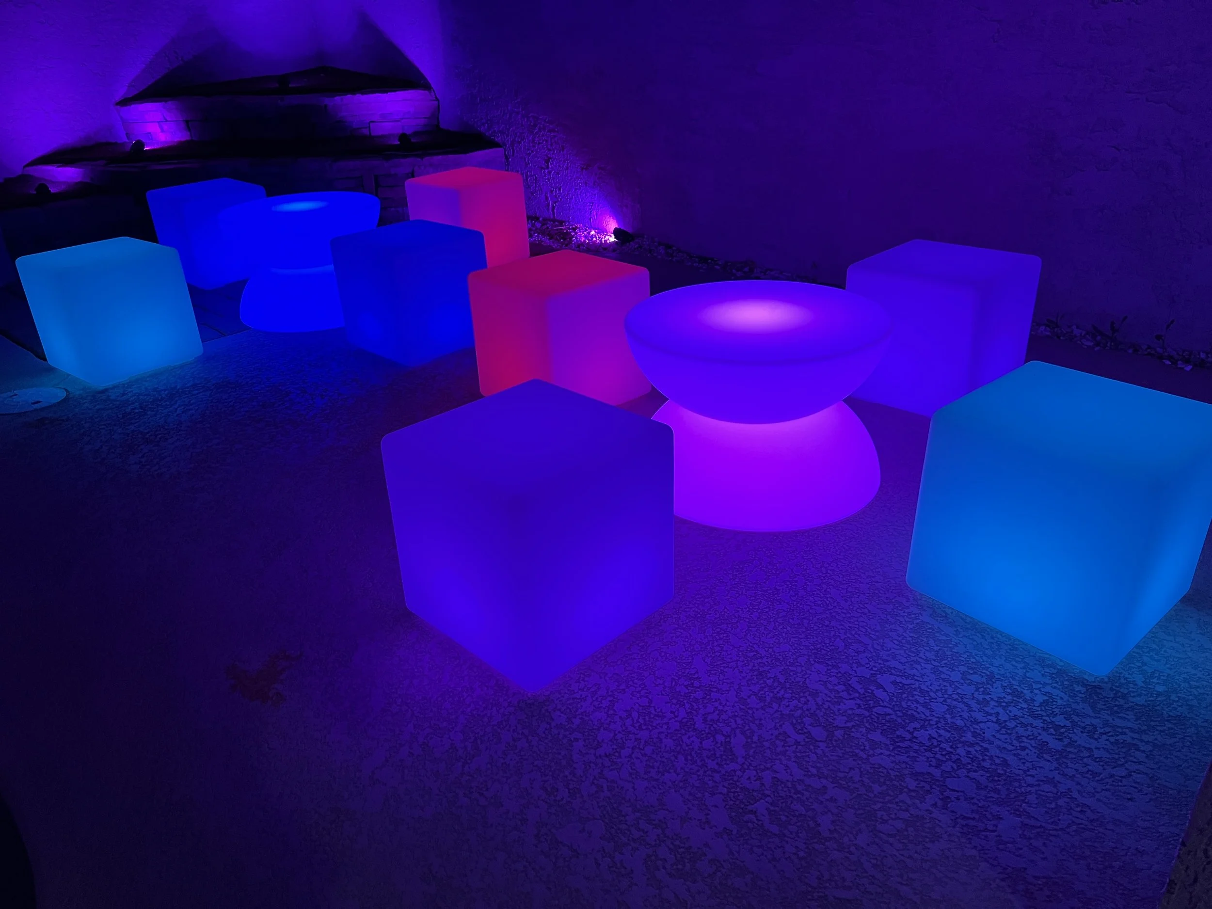 Illuminated colorful cubes and spheres in a dark room with purple ambient lighting.