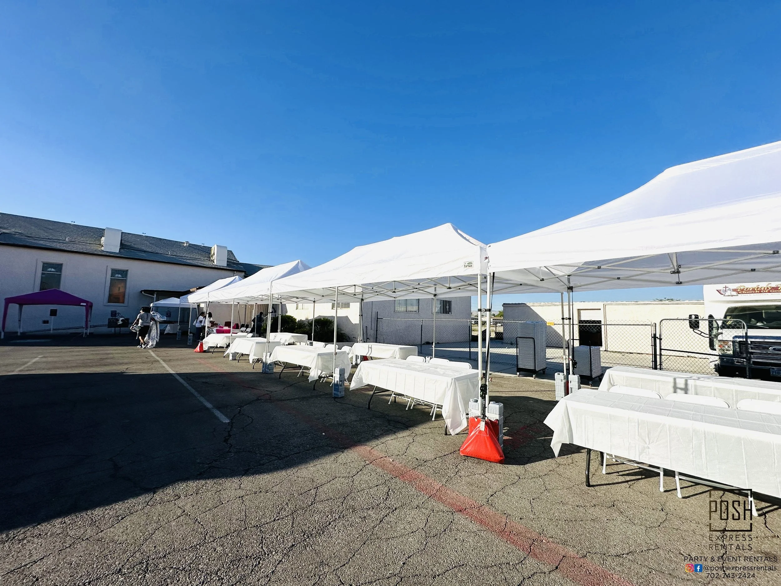 Outdoor event setup with white tents and tables