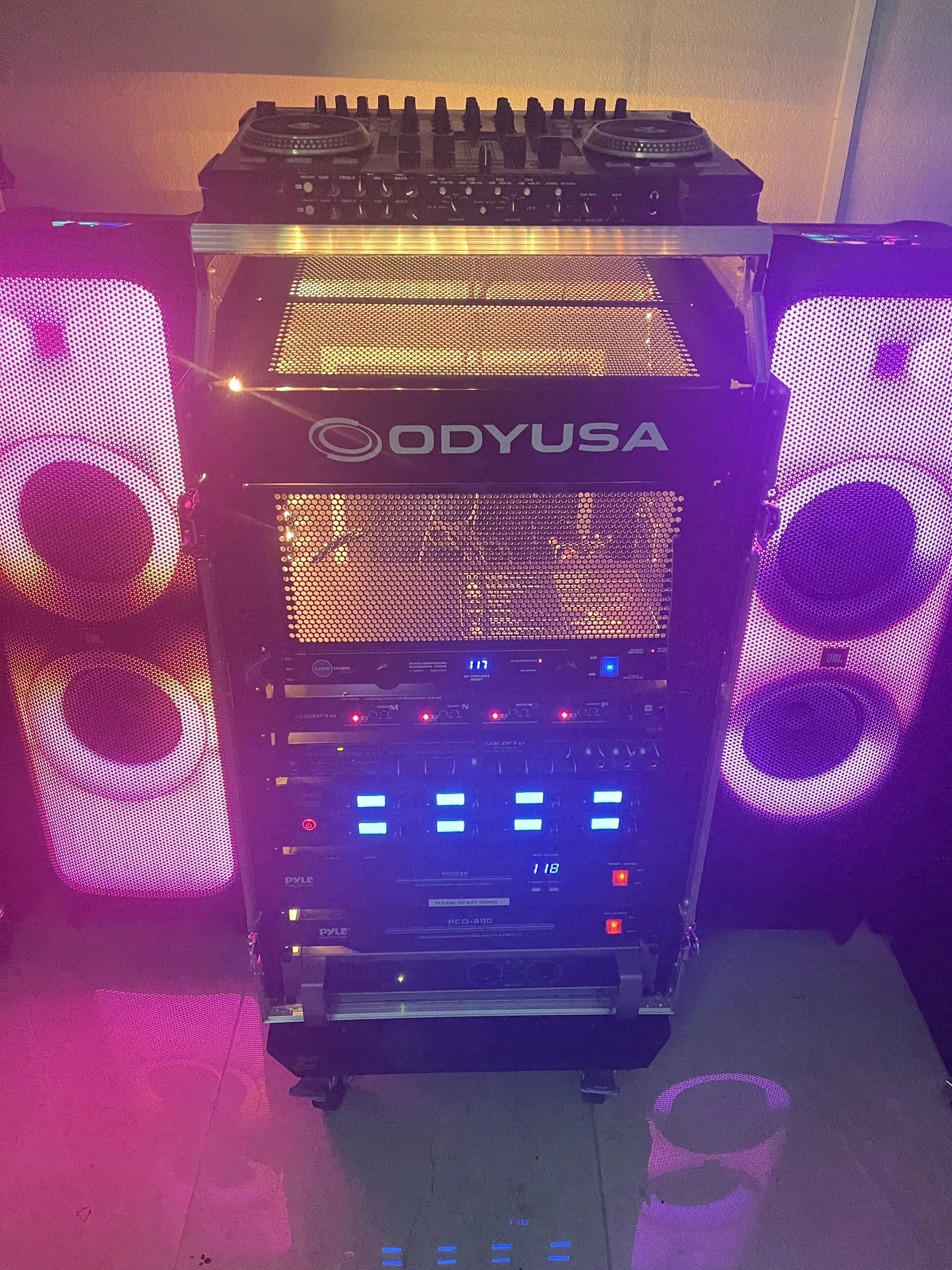 Professional DJ equipment with speakers and control panel, featuring Odysse branding, lit with colorful lights.