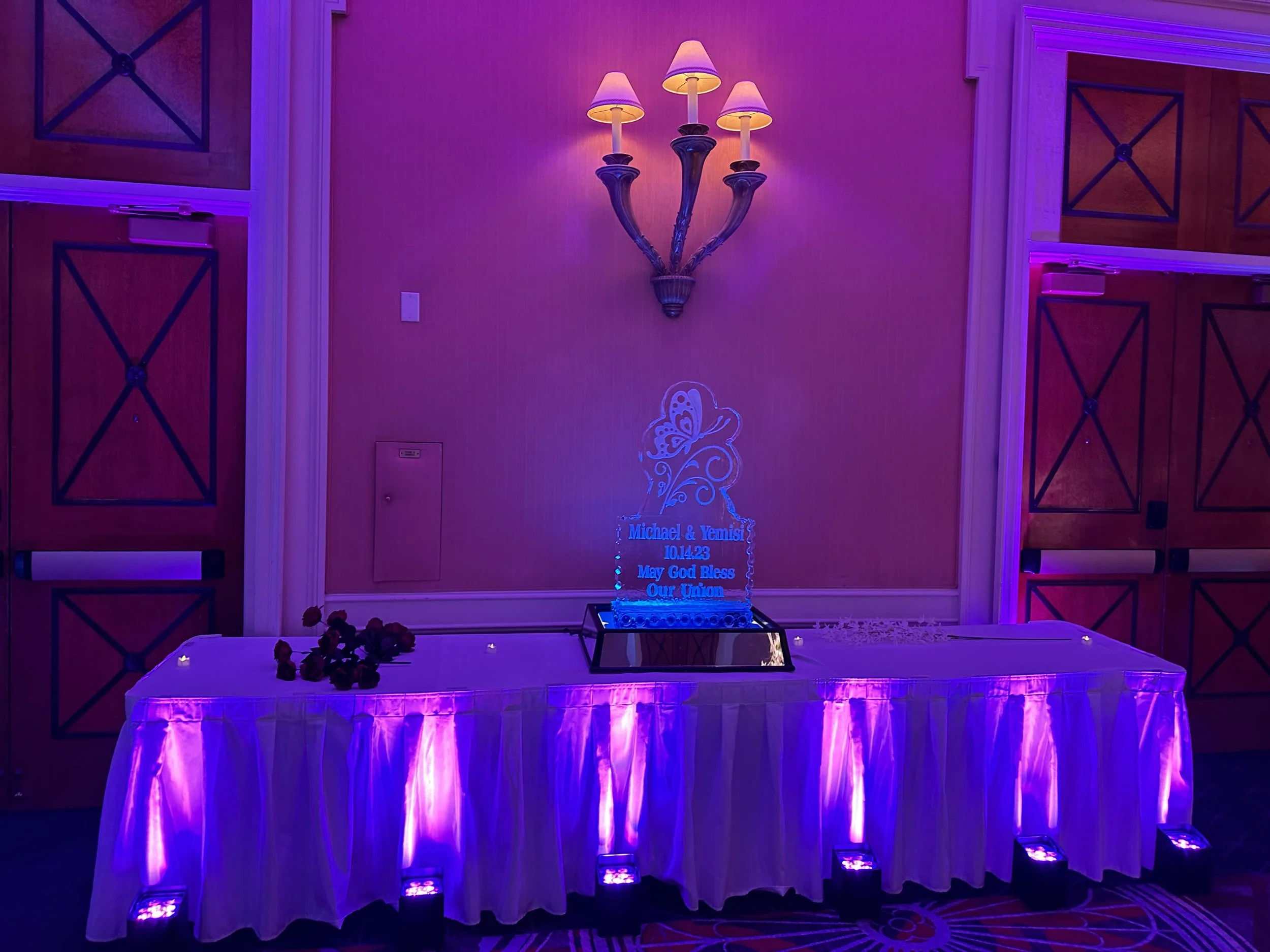 Colorful wireless LED uplights illuminating corporate venue and wedding reception space, available through professional party rentals for custom event atmosphere