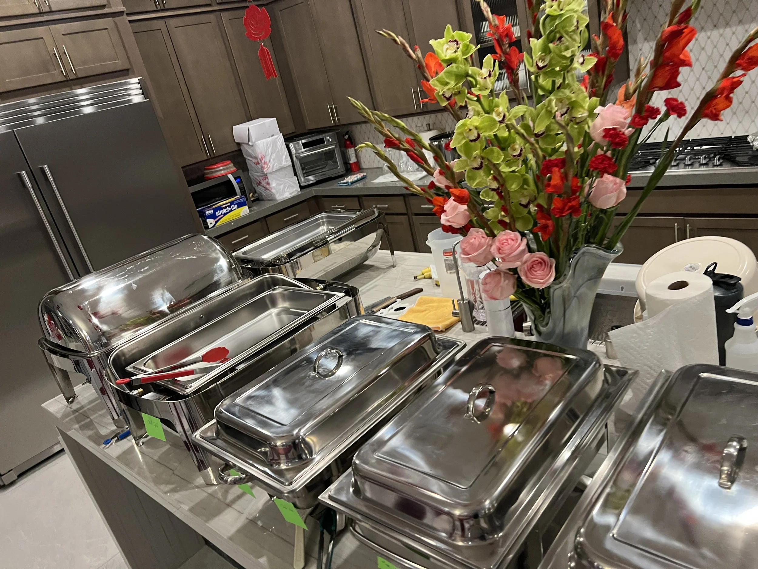 Kitchen setup with buffet chafing dishes and a vase of flowers