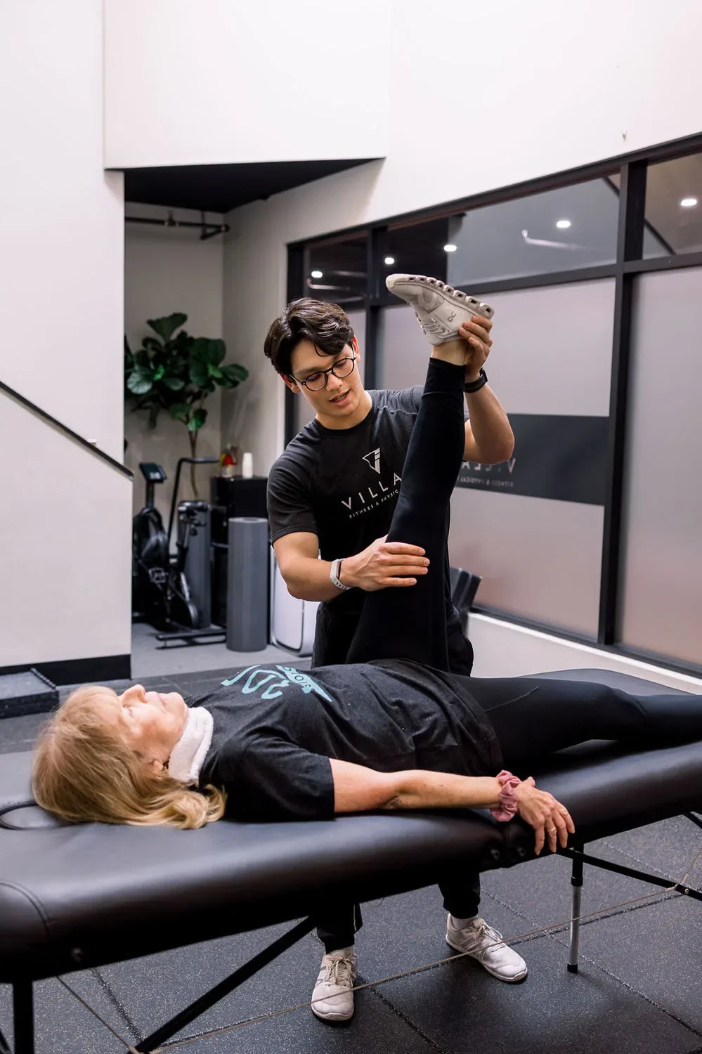 Village Fitness personal trainer supports client to stretch during a one-to-one session in San Marino