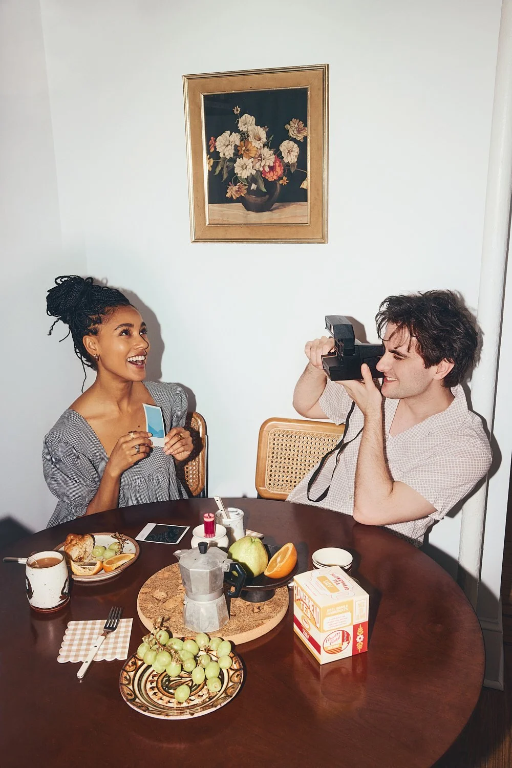 Candid lifestyle photography: couple taking Polaroid photos of each other at the breakfast table by Tara Donne, photographer & director working in NYC & LA