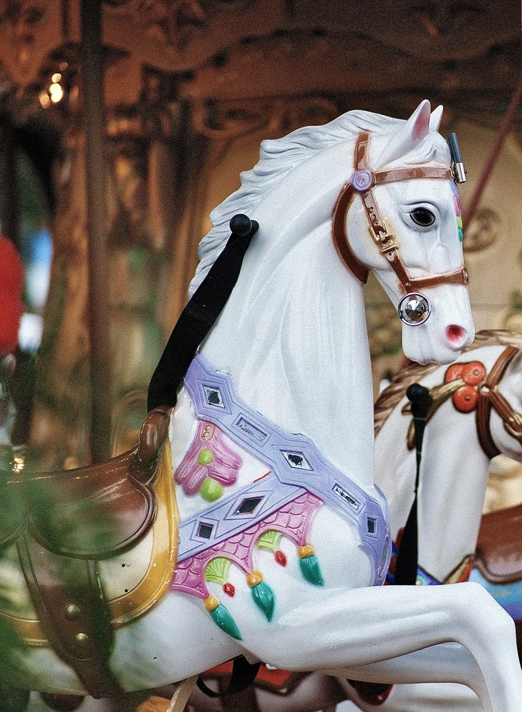 Colorful carousel horse with a decorative saddle and bridle, part of a carousel ride.