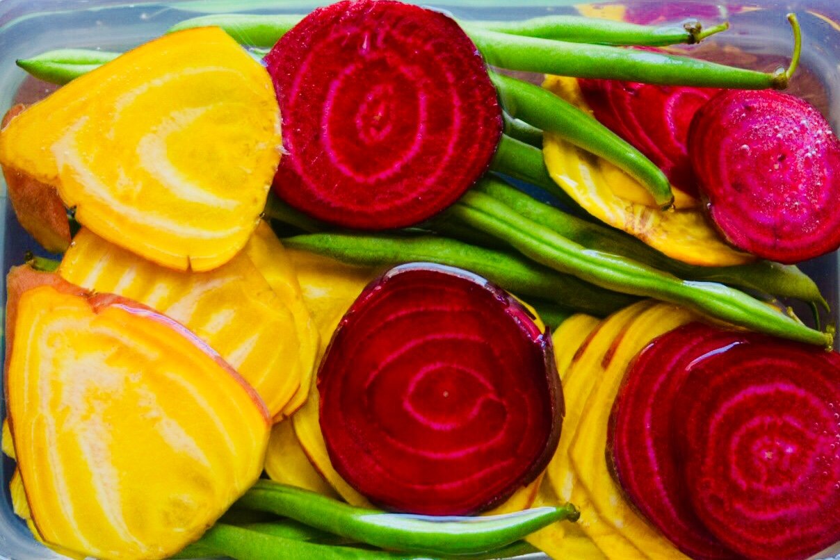 Sliced yellow beets, red beets, and green beans in a bowl.