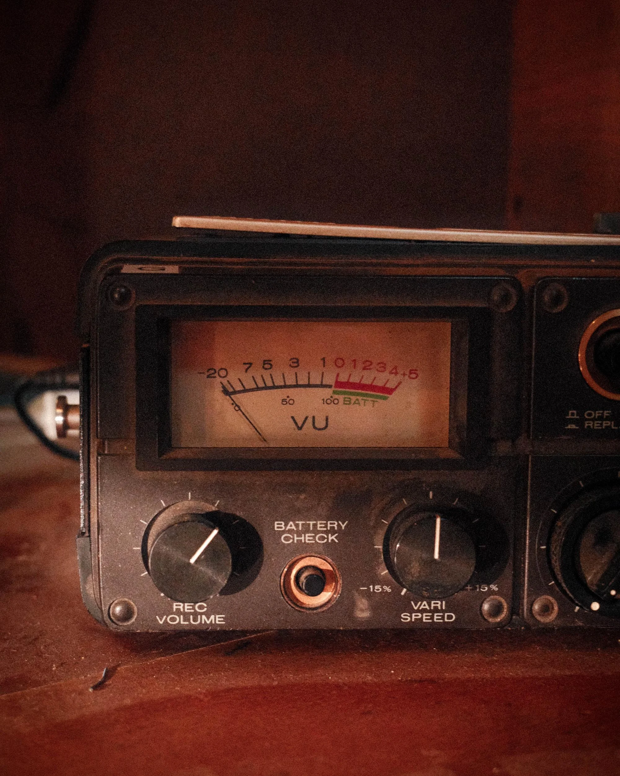 Close-up of a vintage audio equipment panel with a Vu meter, knobs for REC VOLUME, VARI SPEED, and other controls, placed on a wooden surface.
