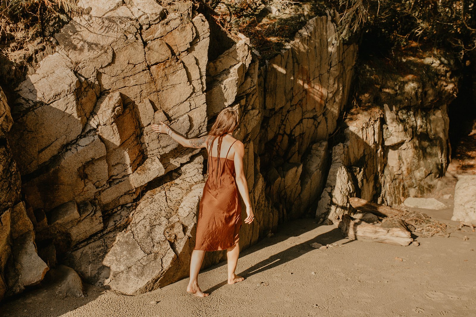 Woman with hand on rugged west coast rock wall