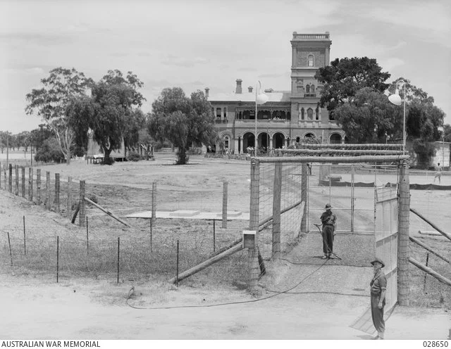 Mansion surrounded by barbed wire security fence. Source: Australian War Memorial