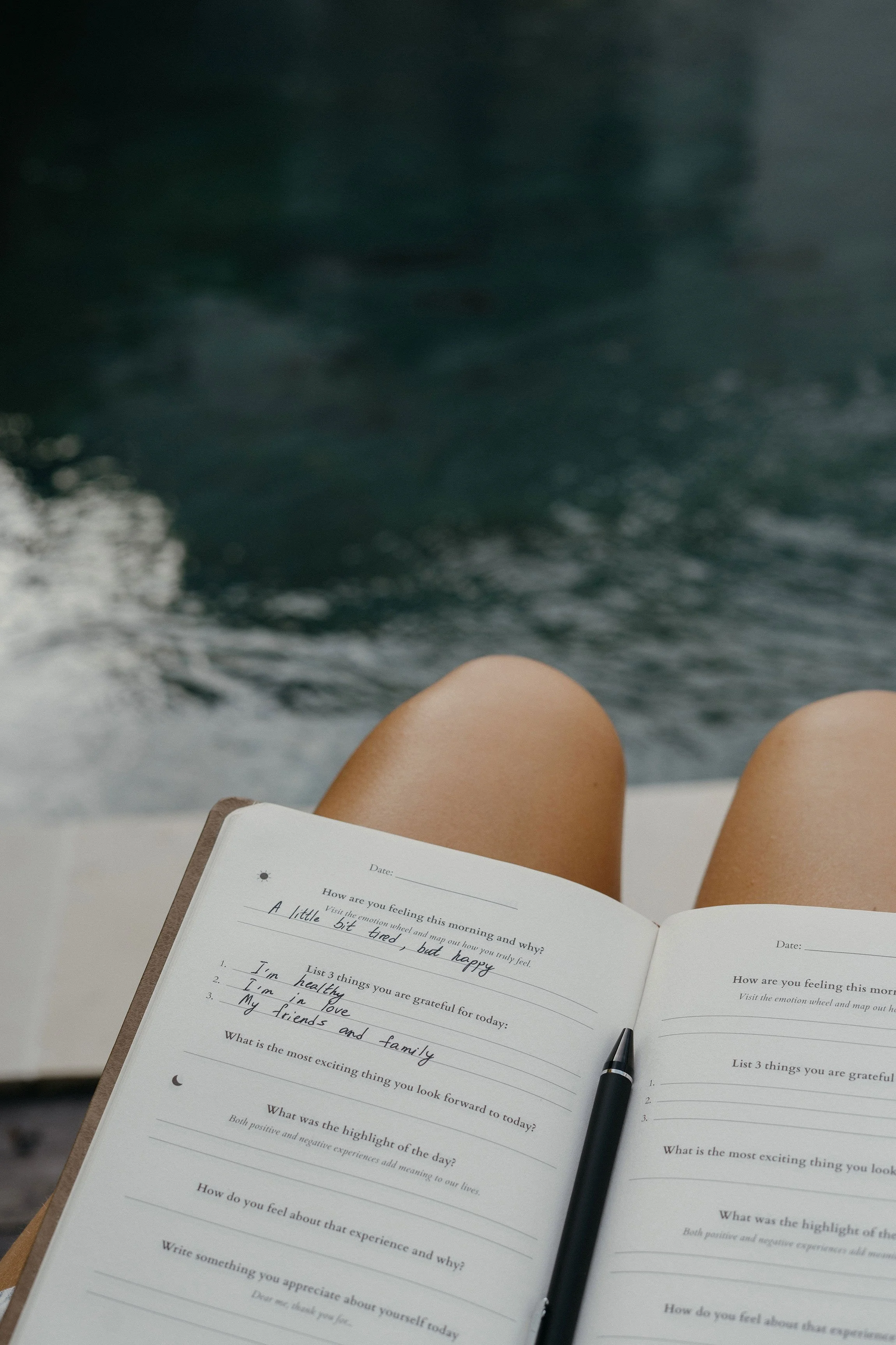 open journal with writing and pencil resting on knee while lounging-Design Mood No-Regret Checks tool by ARDISENOSTUDIO