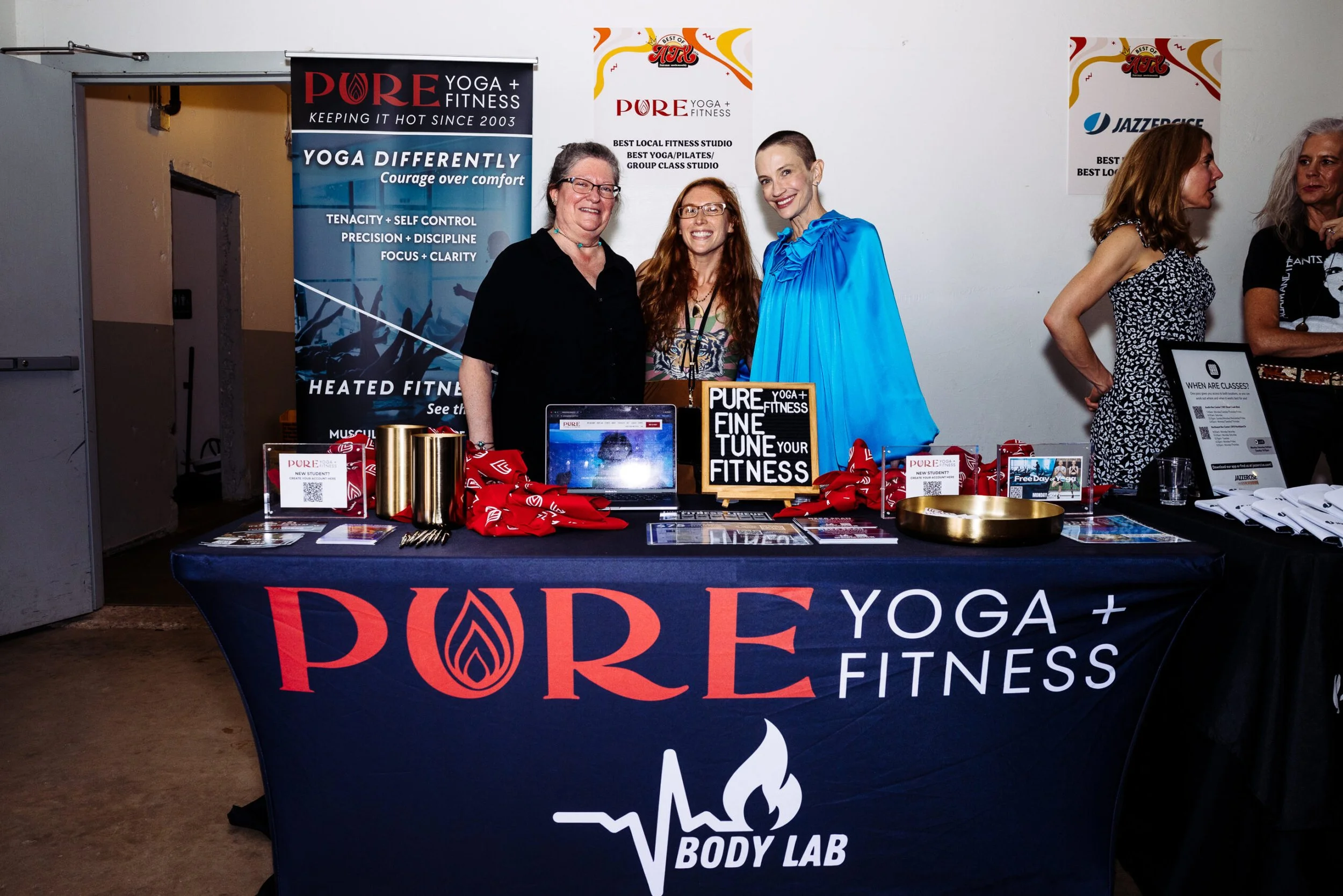 PURE Yoga + Fitness management team behind a booth with banners that read 'PURE Yoga + Fitness' and 'Body Lab' at the Best of ATX awards event.