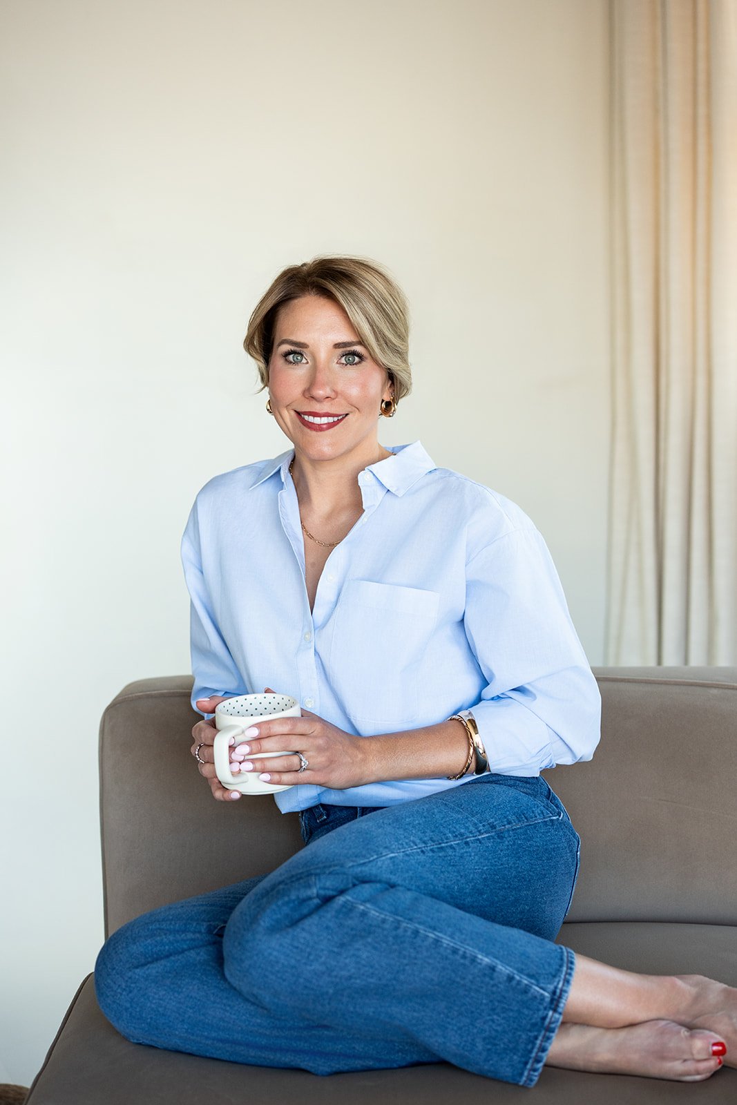 Brittany Baker LCSW and therapist casually sitting on a couch with coffee in Greenwood Village, CO