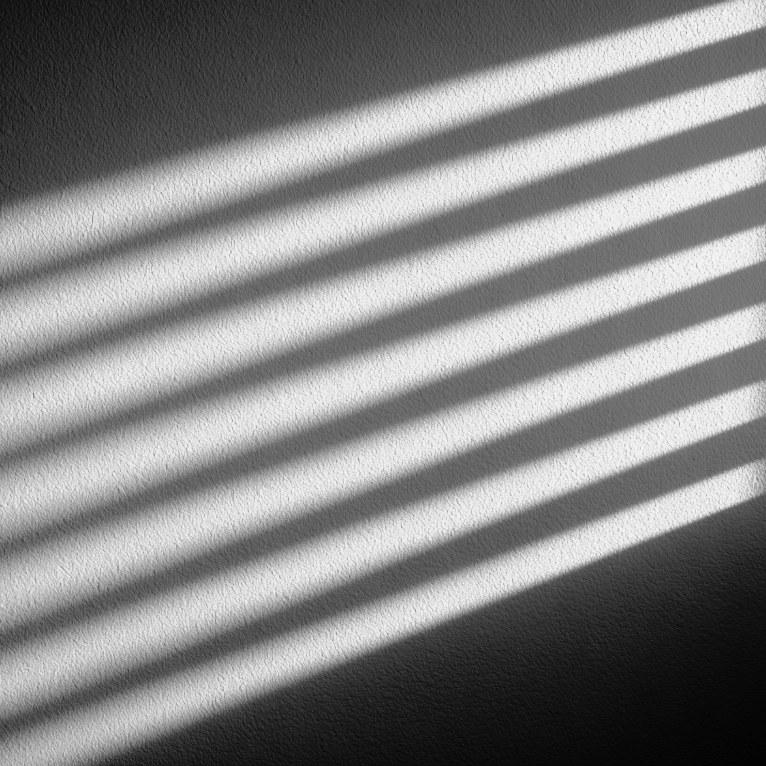 Sunlight casting shadows of blinds on a textured wall.