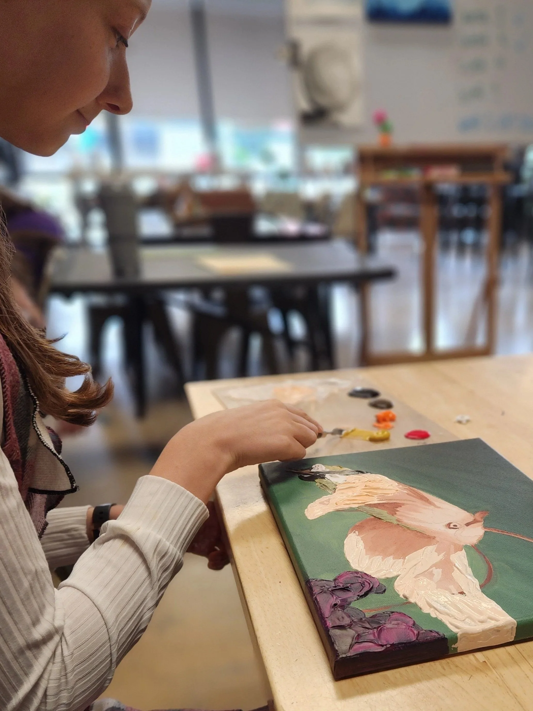 A child painting on a canvas in the kids art series class at the art house st augustine