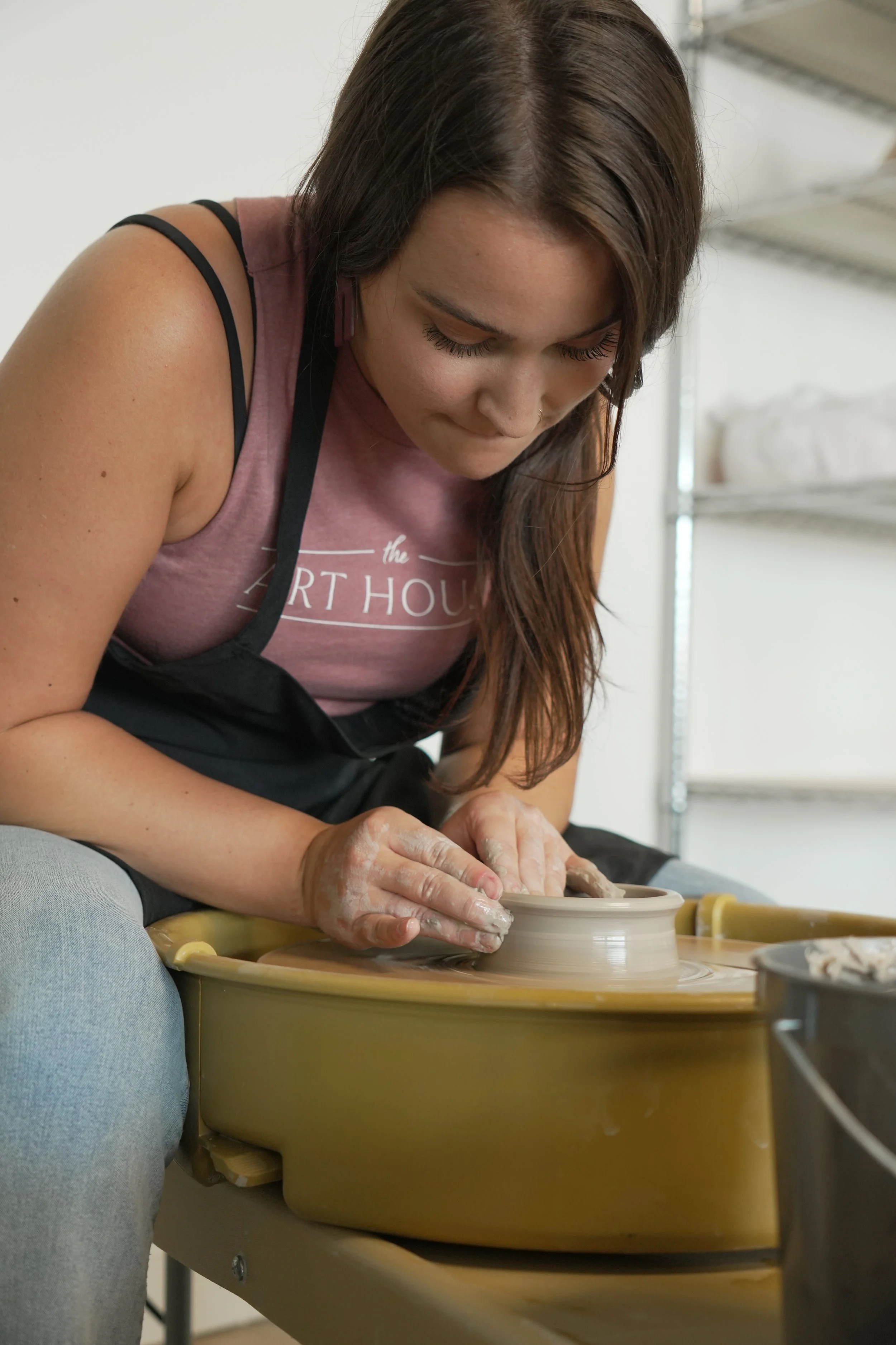 A woman shaping clay on a pottery wheel at the art house st augustine