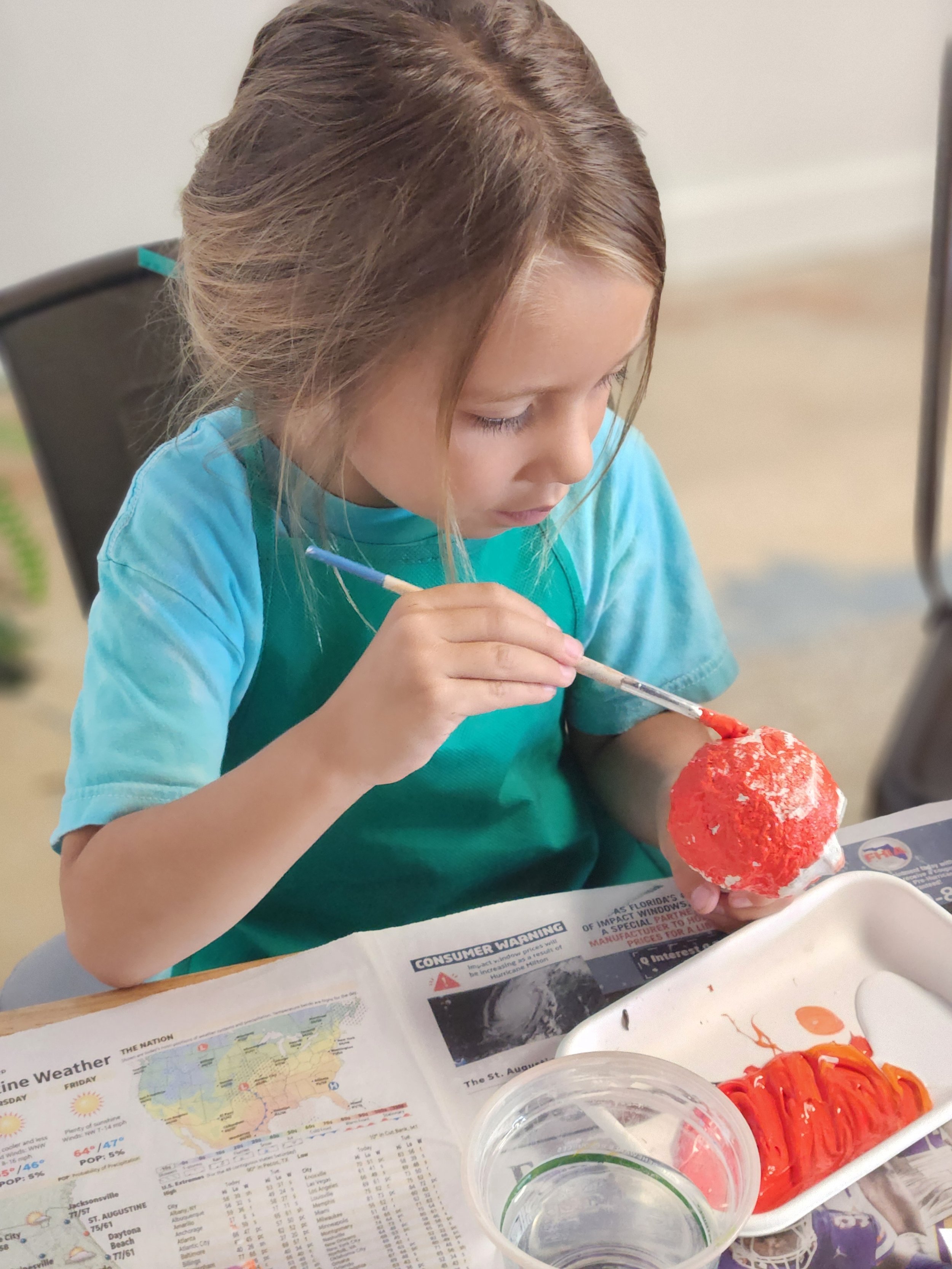 A child painting a paper machete craft made in a camp at the art house st augustine