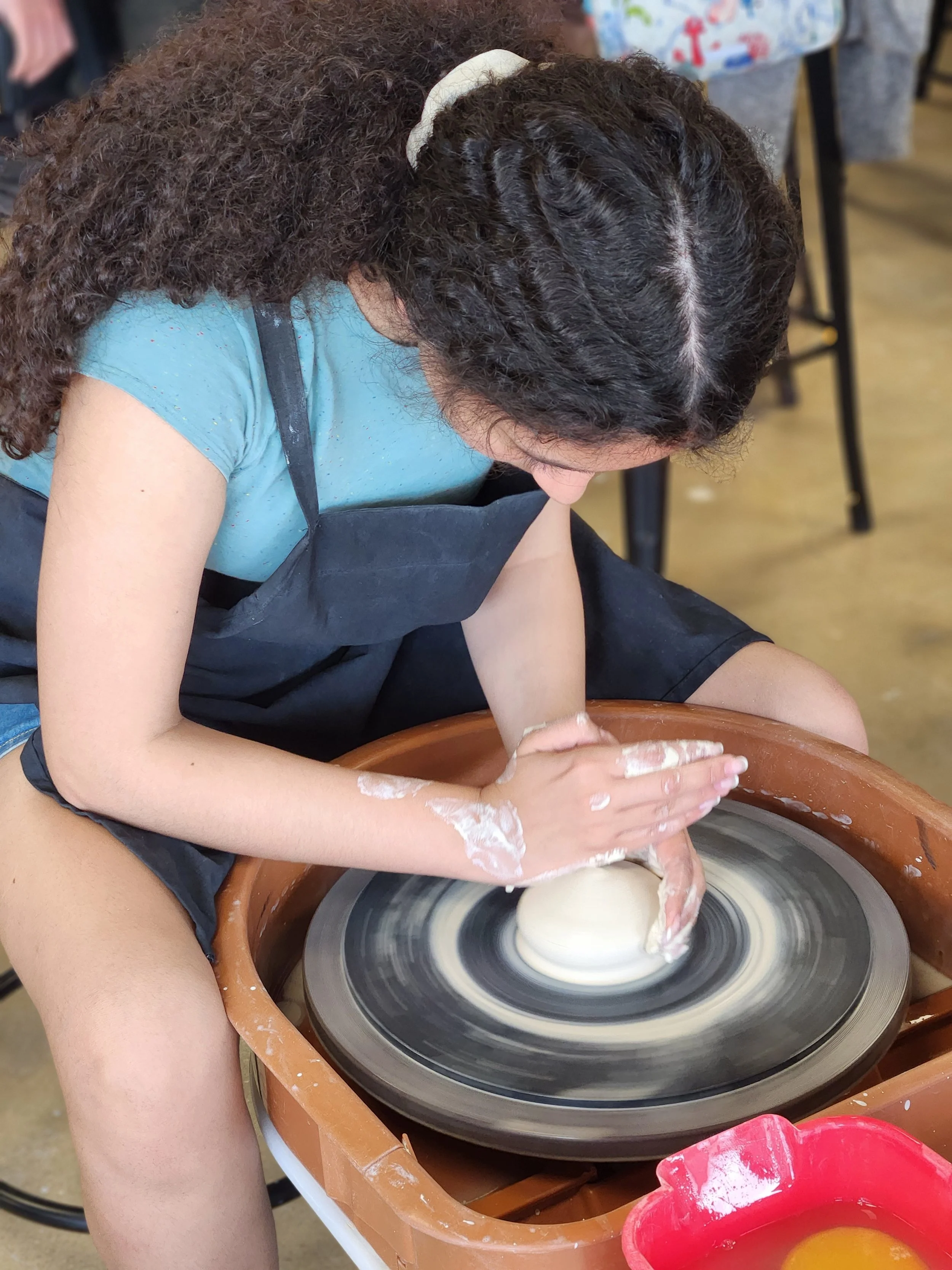 Teenager throwing pottery on the pottery wheel in teen wheel throwing class at the art house st augustine