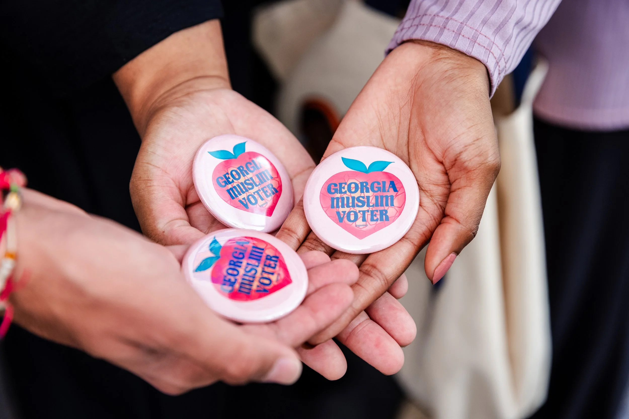 GAMVP senior community organizer Salik holds a large sign that says “Georgia – I’m registered to vote!” while members Xan-Rhea and Hibah point to the sign from each side