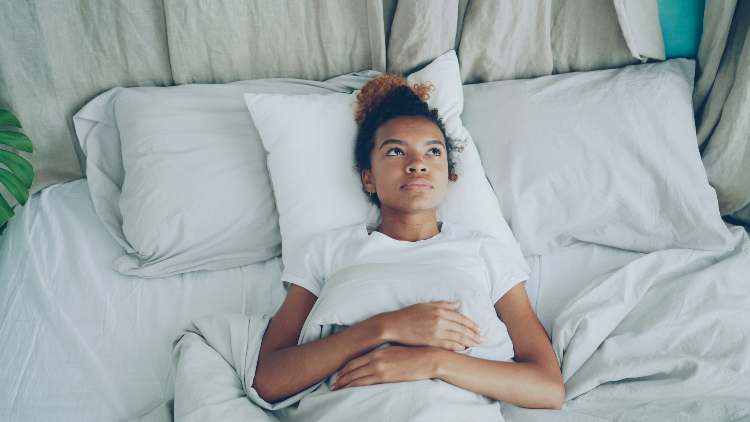 Woman lying awake in a dark bedroom looking at the ceiling, representing sleep disruption during perimenopause and menopause