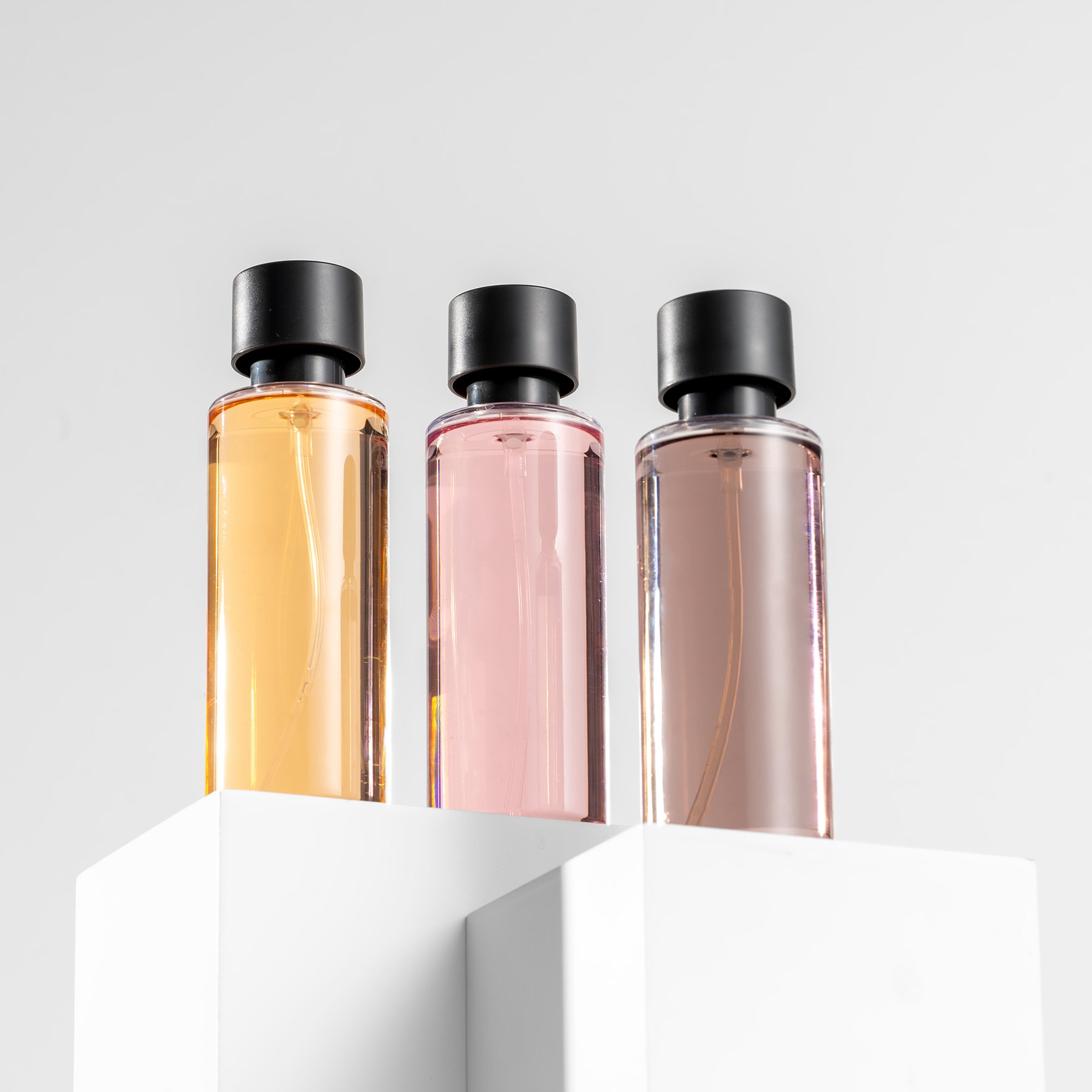 White rectangular product photography risers displaying three perfume bottles