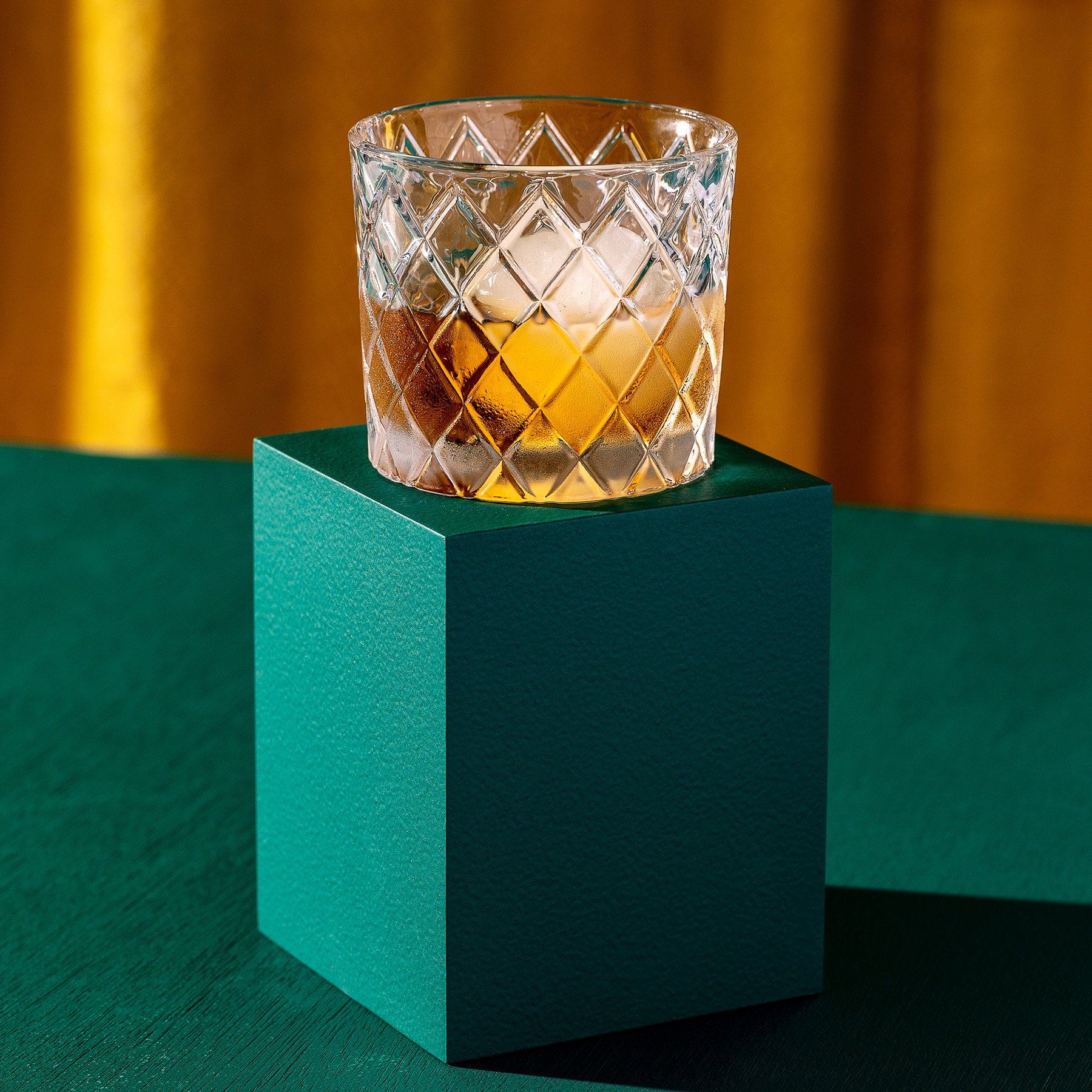 One green rectangular product photography riser displaying a glass of whiskey